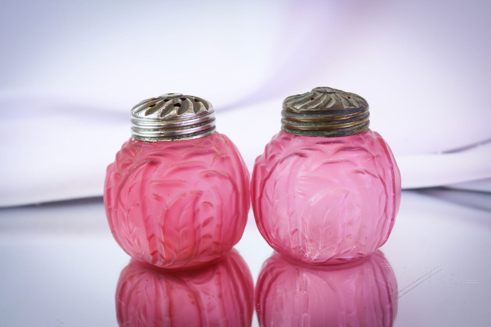Pair Northwood Leaf Mold Victorian Cranberry Satin Shakers: A fine pair of Northwood cranberry satin Leaf Mold pattern shakers. This pair glows brightly under black light. Both are in a rich satin finish. Each measures 2 1/2" tall. Both have the original lids.