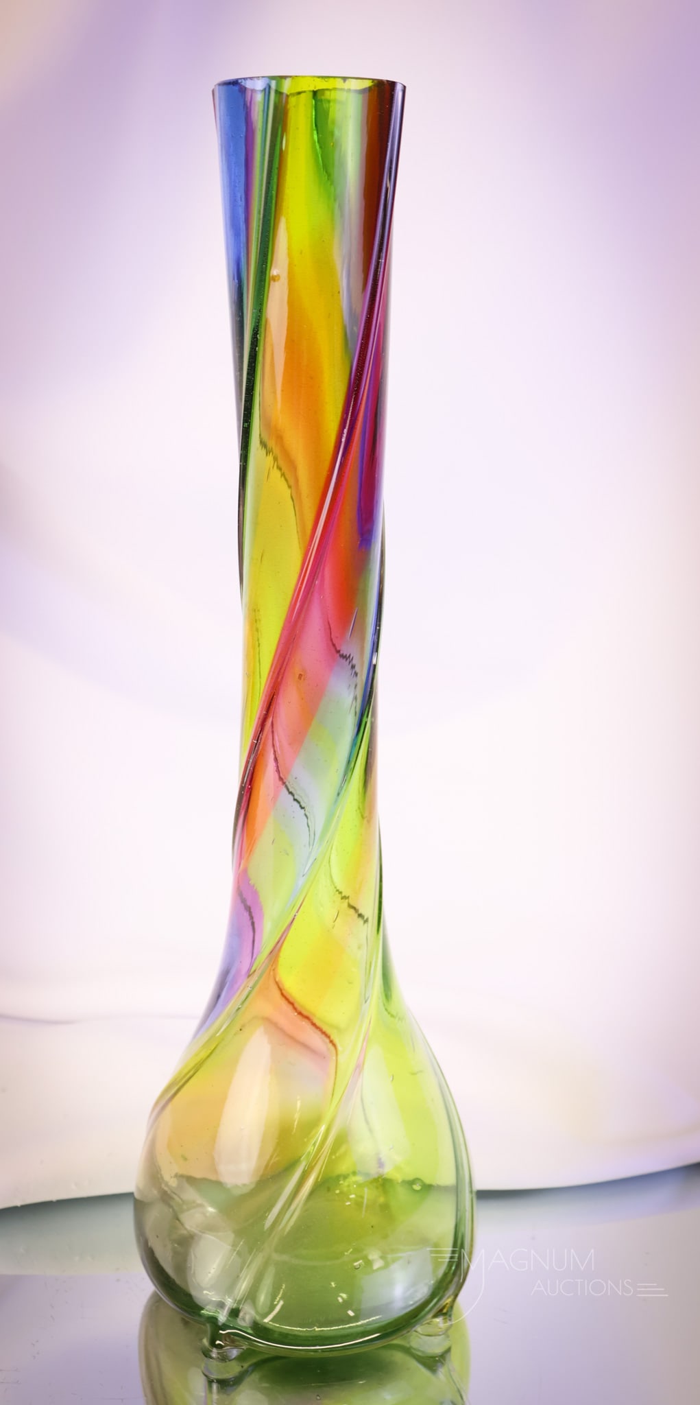 14" Rainbow Ribbed Swirl Art Glass Vase: A wonderful 14" tall rainbow art glass ribbed swirl vase. This piece has vibrant colors and a sleek form. SHIPPING NOTICE: If you choose not to utilize the LiveAuctioneers LiveShip program, MAGNUM AUC