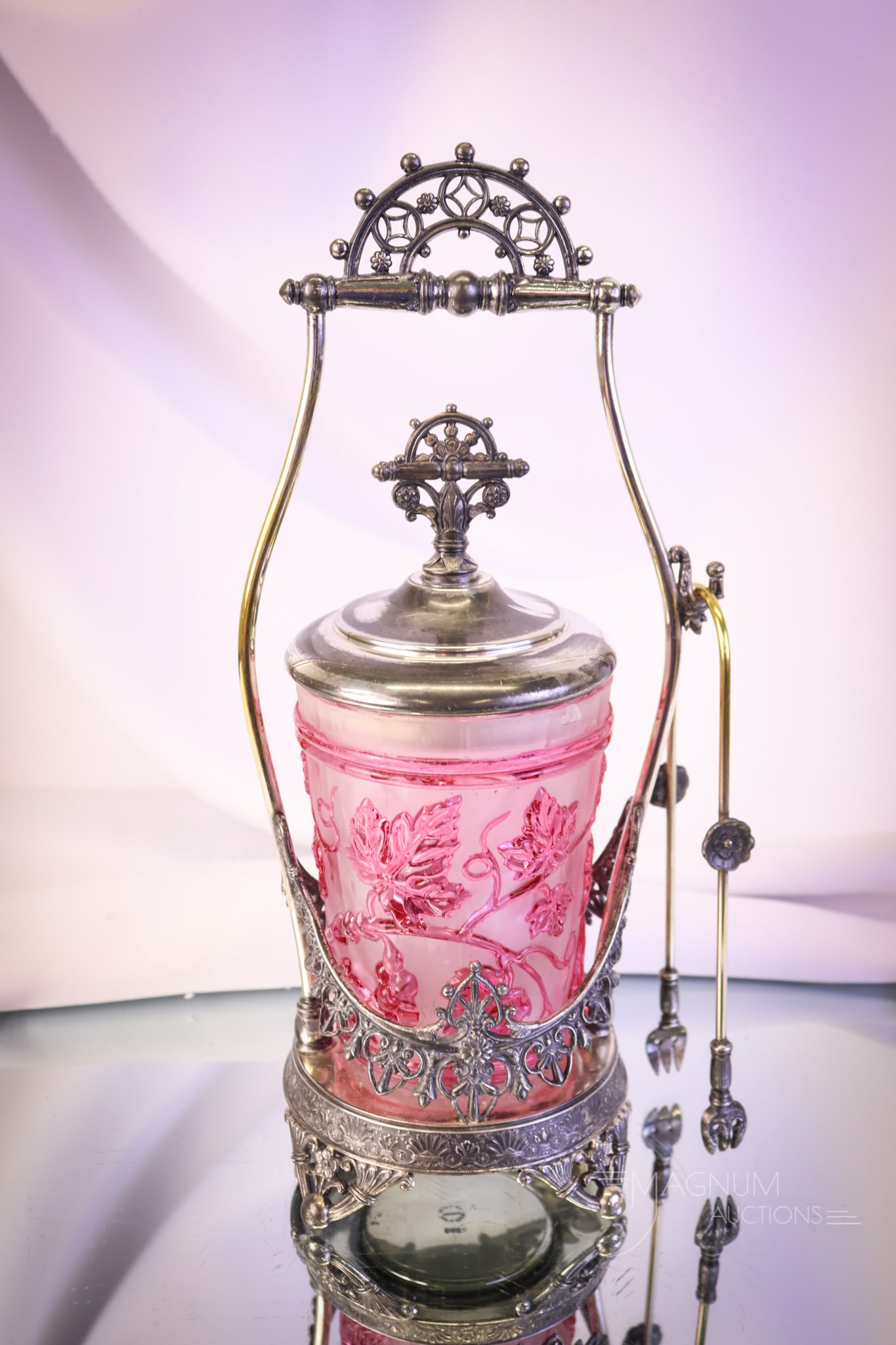 Tufts Silverplate Victorian Cranberry Embossed Pickle Castor: An unusual find in a marked Tufts silverplate pickle castor. This frame is quite ornate and detailed. The pickle jar is done in a molded relief of grapes and grape leaves and further enhanced by cranb