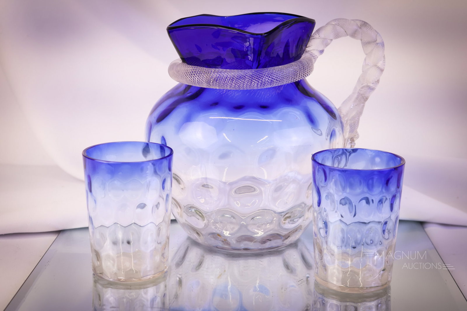 Rare Victorian Bluerina Glass Water Pitcher & Tumblers: A striking find in Victorian Bluerina, cobalt blue to clear glass. This offering includes a water pitcher and two matching tumblers. The pitcher has a rope handle around the neck. The tallest measures