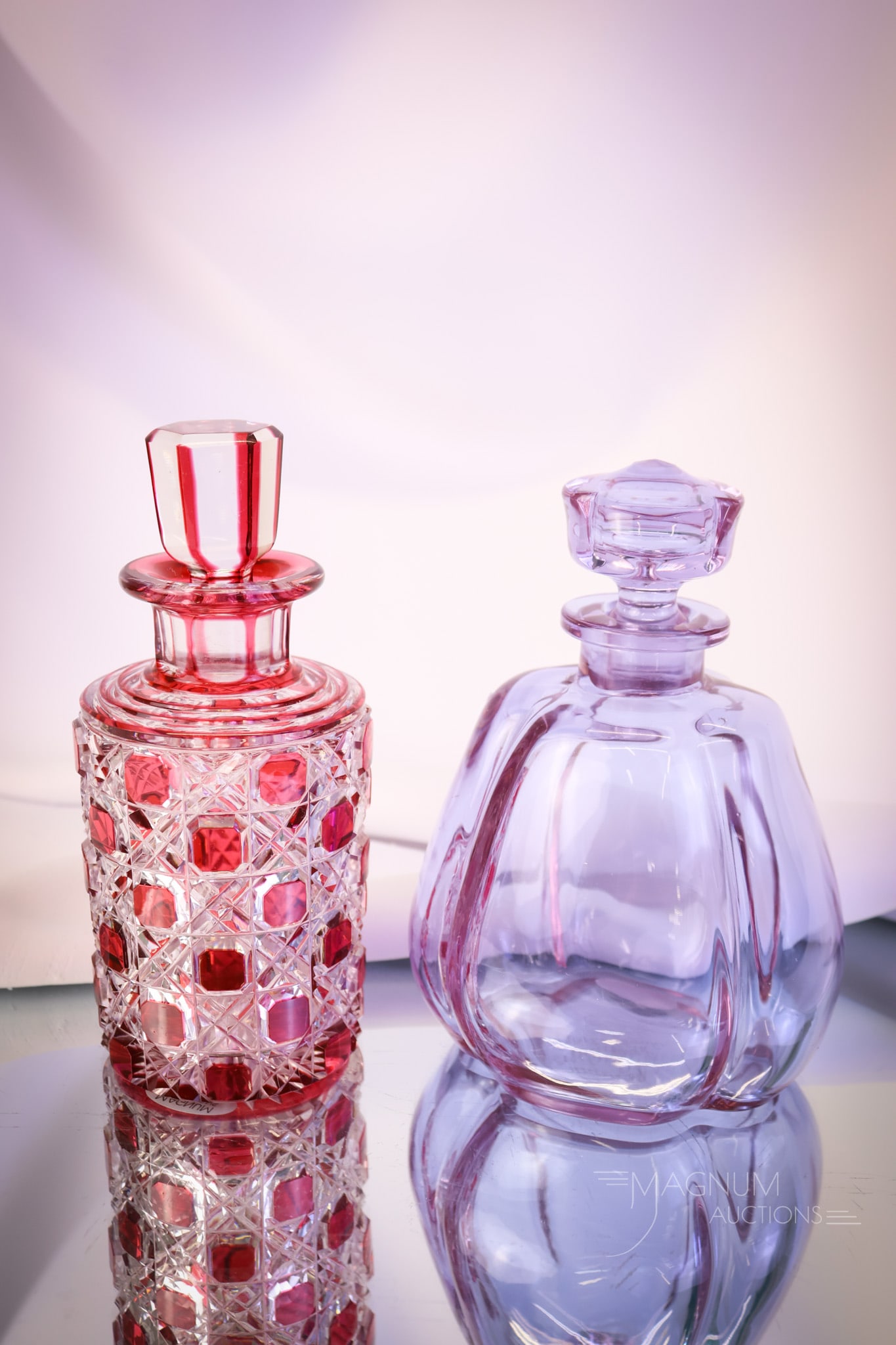 2 pc Perfume Cologne Bottles Moser Alexandrite and Cranberry Cut to Clear: Two beautiful finds in art glass, cologne perfume bottles. The first is a signed Moser Alexandrite example with a lobed body and matching stopper. The second is a cranberry cut to clear with a Button 