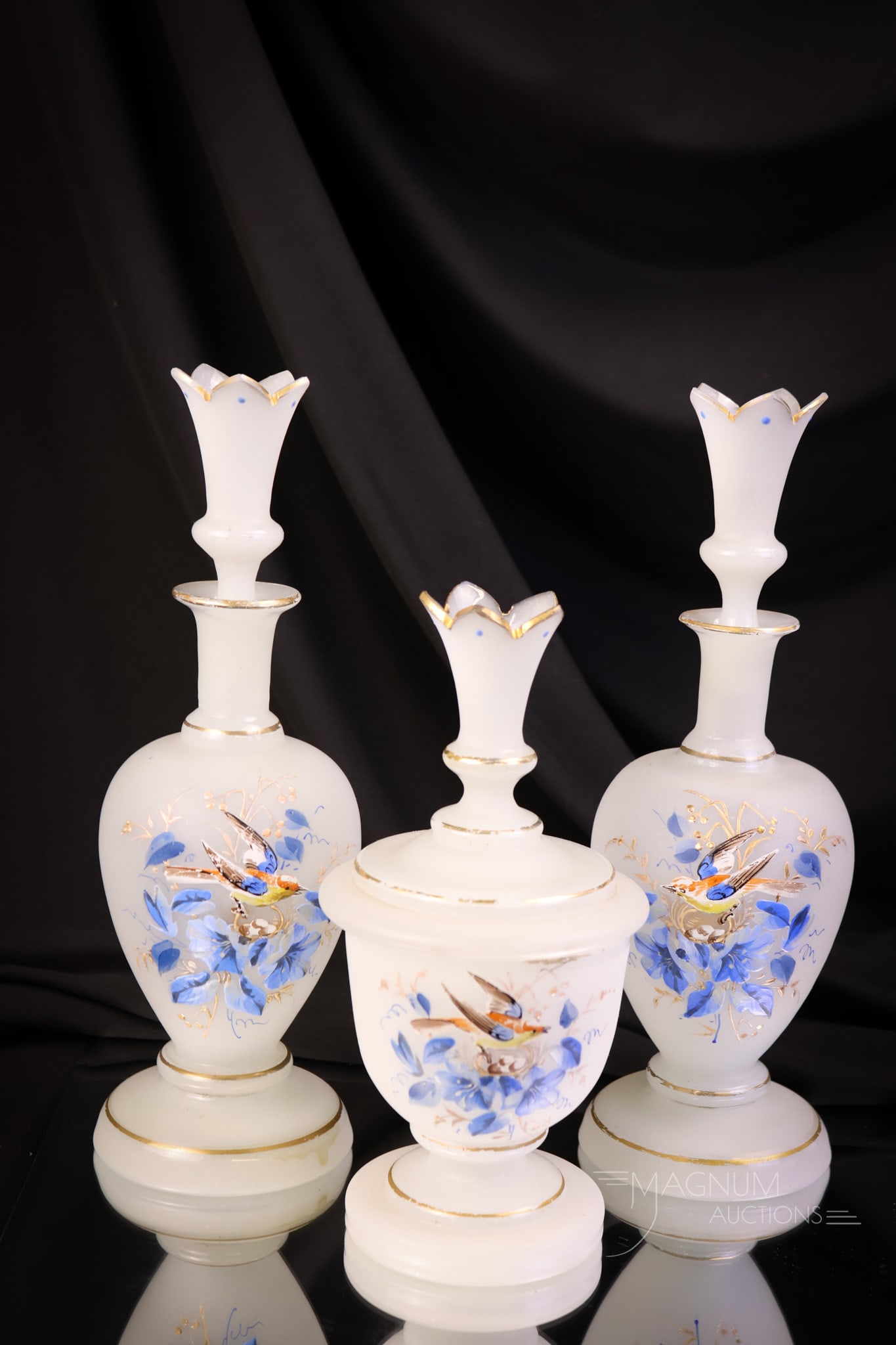 Victorian Enamel Gilt Decorated Opaline Three Bottle Vantiy Cologne Castor Set: A fine three-piece set in white opaline enamel and gilt decorated Victorian glass. The set features crown-form tops and stoppers on each piece. The tallest of the set measures 10". SHIPPING NOTICE: If