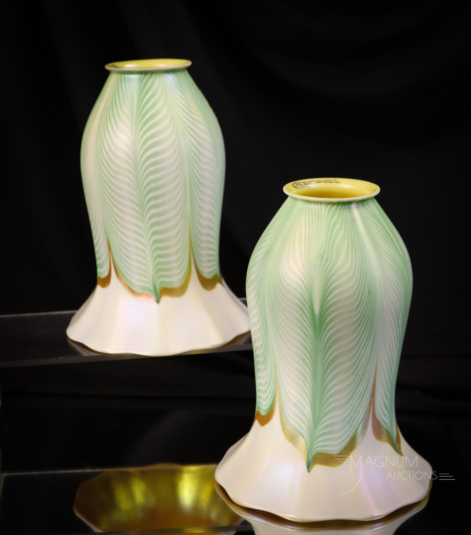 Pair of Signed Quezal Pulled Feather Art Glass Shades: A select offering of a pair of signed Quezal art glass pulled feather shades. The feathers are green and gold with white. The shades have a marvelous golden interior. The shades measure 7" tall, 5"