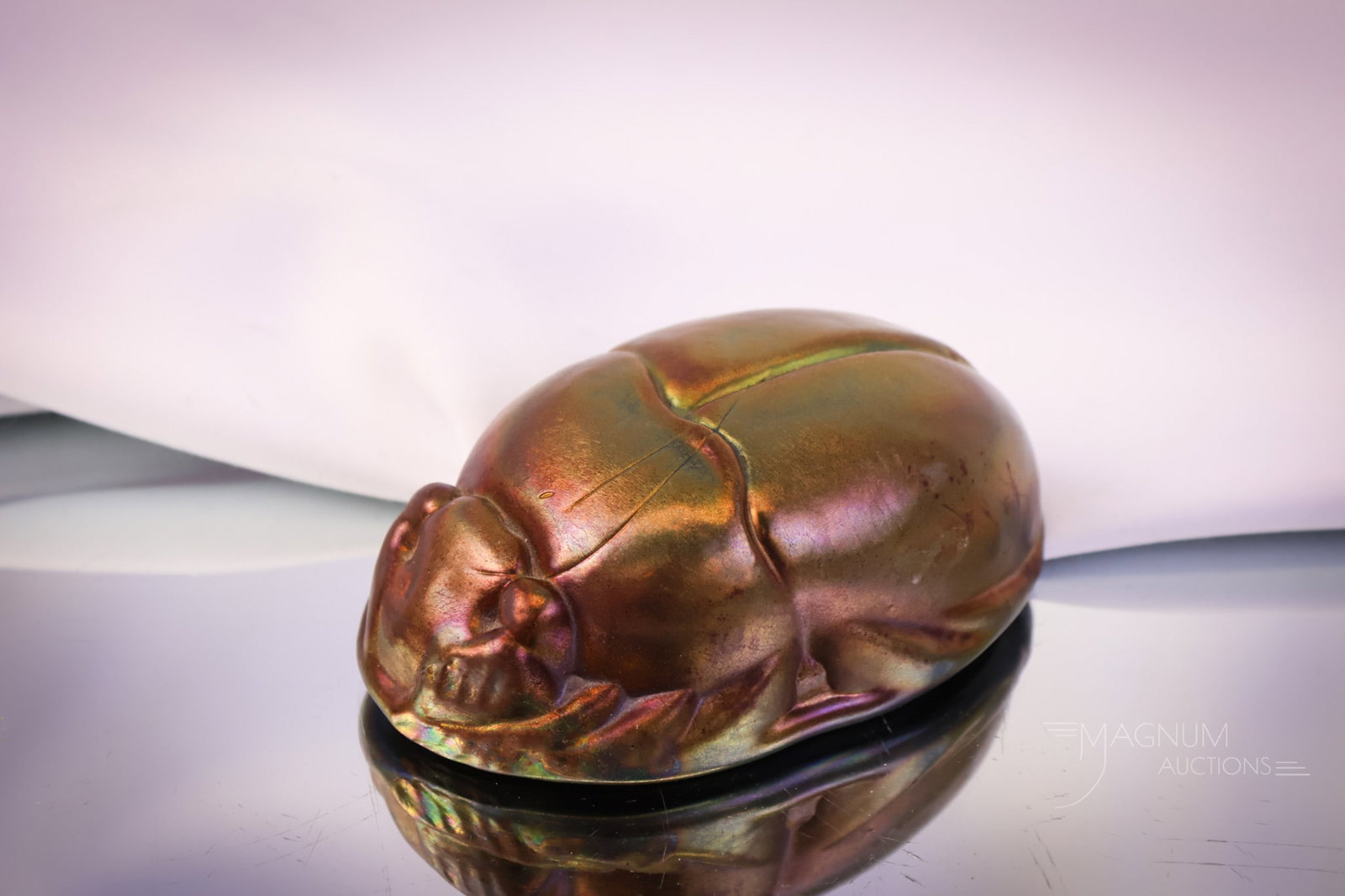 Art Glass Iridescent Scarab Paperweight: A beautiful find in an art glass paperweight. This is a figural scarab with radiant iridescent finish to the glass. This piece is unsigned. The paperweight measures 1 1/2" by 4 1/2". SHIPPING NOTICE: 
