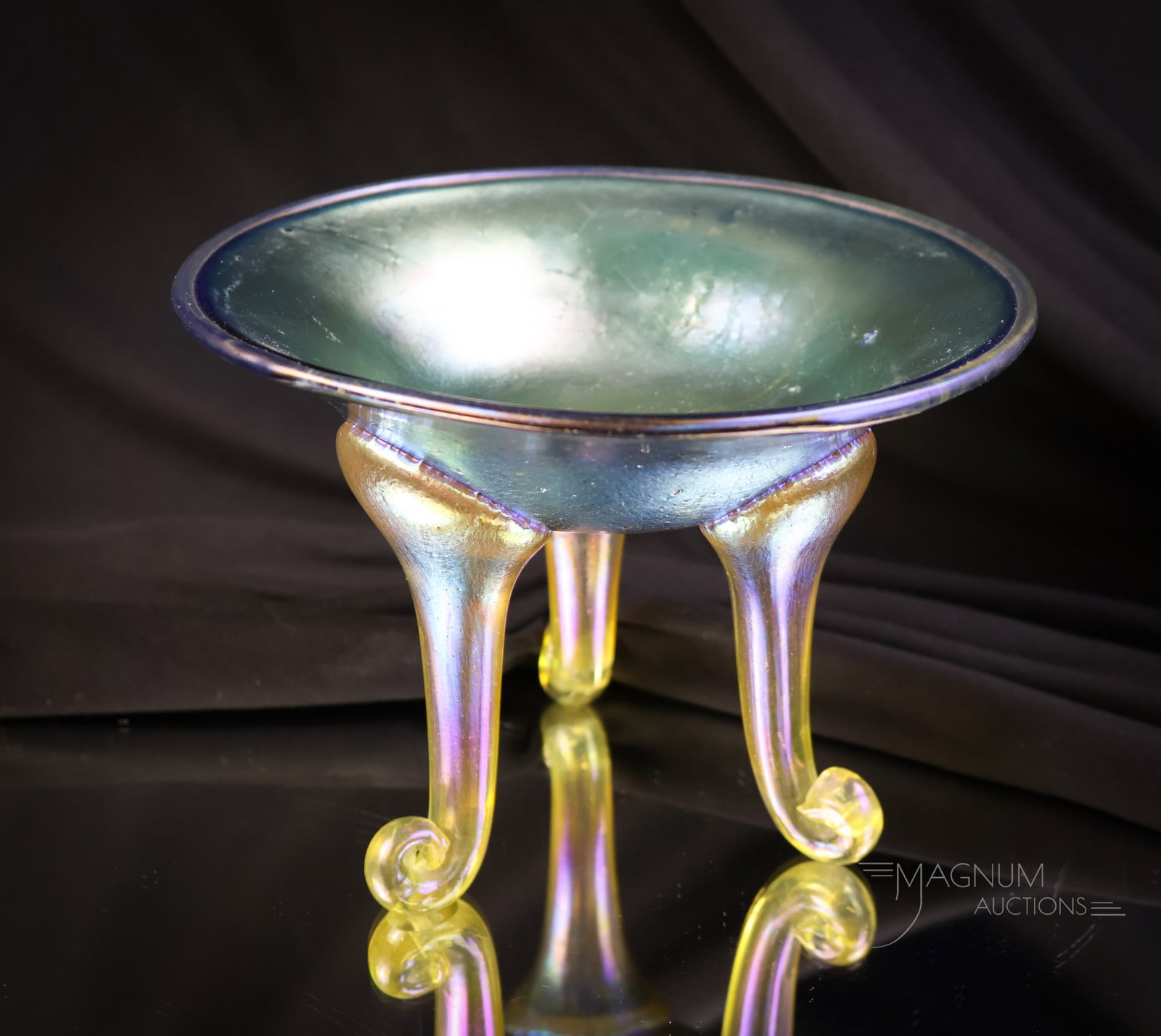 Loetz "Norma" Blue Iridescent Footed Applied Glass Bowl: A beautiful and unusual find in Loetz glass. This is a "Norma" footed bowl. This piece has a blue iridescent body and three applied silverly-yellow color legs. The piece measures 4 1/2" tall and 6 1/4