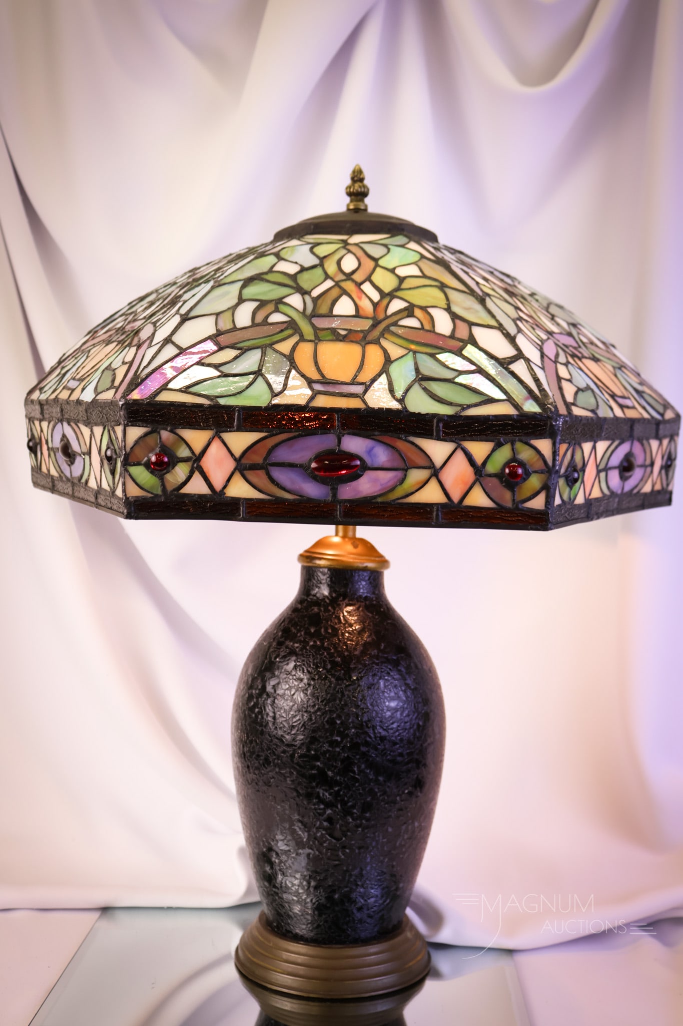 Handel Glass Lamp Base Leaded Art Glass Shade: A nice find for decorating your home. This lamp features a Handel glass lamp base topped with a leaded art glass shade. The lamp measures 23" tall and 17" wide. The base exhibits a crack in the glass.