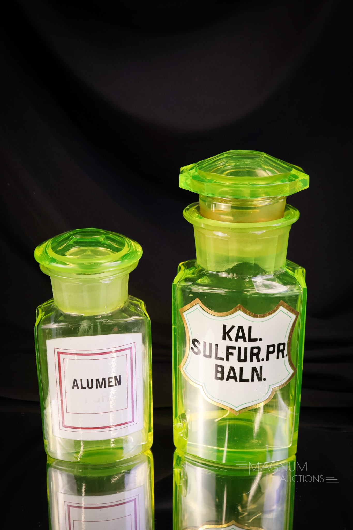 2 pc Lot Antique Victorian Uranium Vaseline Glass Apothecary Bottles Enameled Labels: A selection of two antique vaseline uranium glass antique apothecary bottles with enameled labels. They are "Alumen" and "Kal Sul Fur. PR Baln." The tallest measures 8". The second bottle exhibits a c