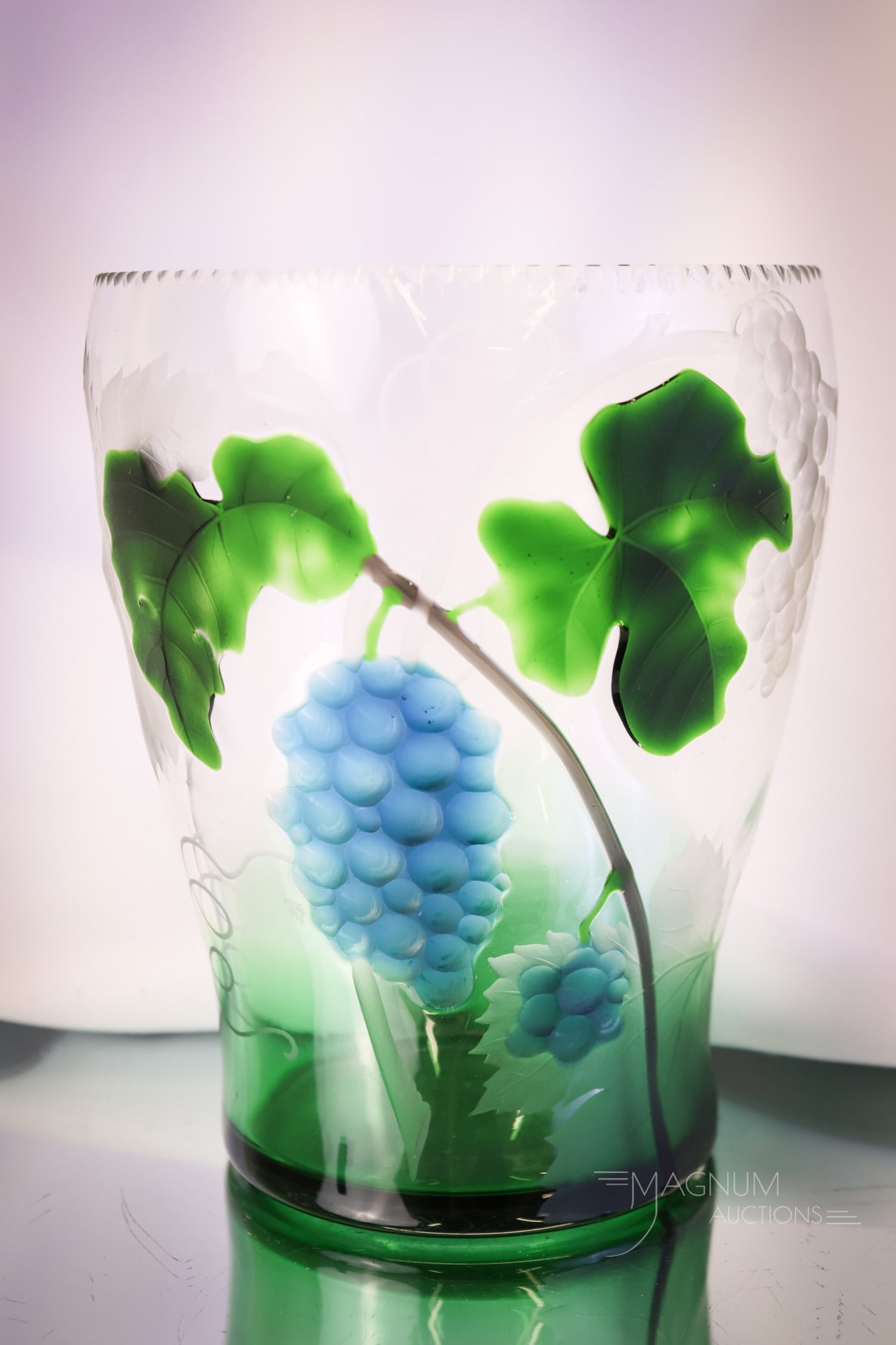 Moser Harrach Marquetry Art Glass Vase with Grapes: A wonderful offering of a Marquetry glass vase decorated with grapes. This piece is attributed to Moser or Harrach Glass. The vase is green to clear. This piece measures 6 1/2" tall and 5 1/2" wide. S