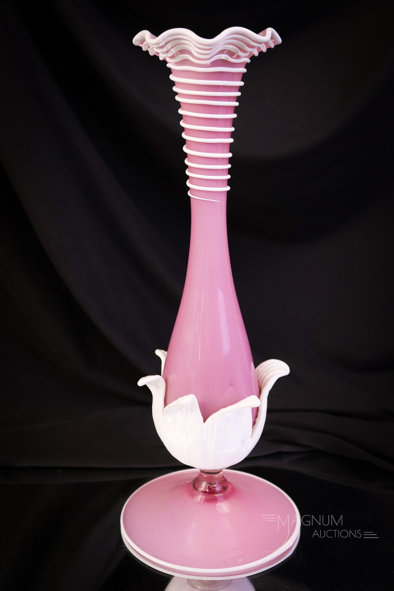 Italian Murano MCM Art Glass 11 1/2" Vase: A pretty in pink MCM Italian Murano applied art glass vase. This piece has a pink body and a white applied foot, leaf decoration, rigaree, and top rim. The vase measures 11 1/2" tall and 4 3/4" wide. 