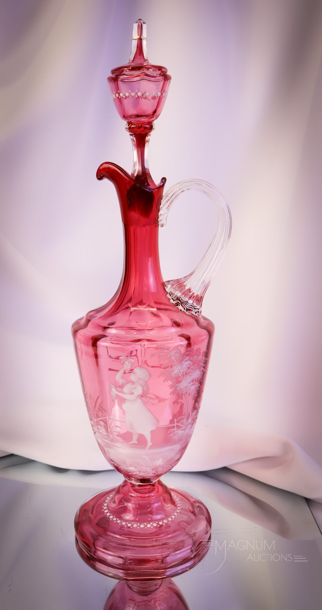 Monumental 17" Cranberry Mary Gregory Victorian Glass Decanter: A 17" tall monumental find in cranberry Victorian glass. This decanter features a Mary Gregory decoration of a young girl with grapes. The decanter features a tall steeple stopper. A grand piece! SHIP