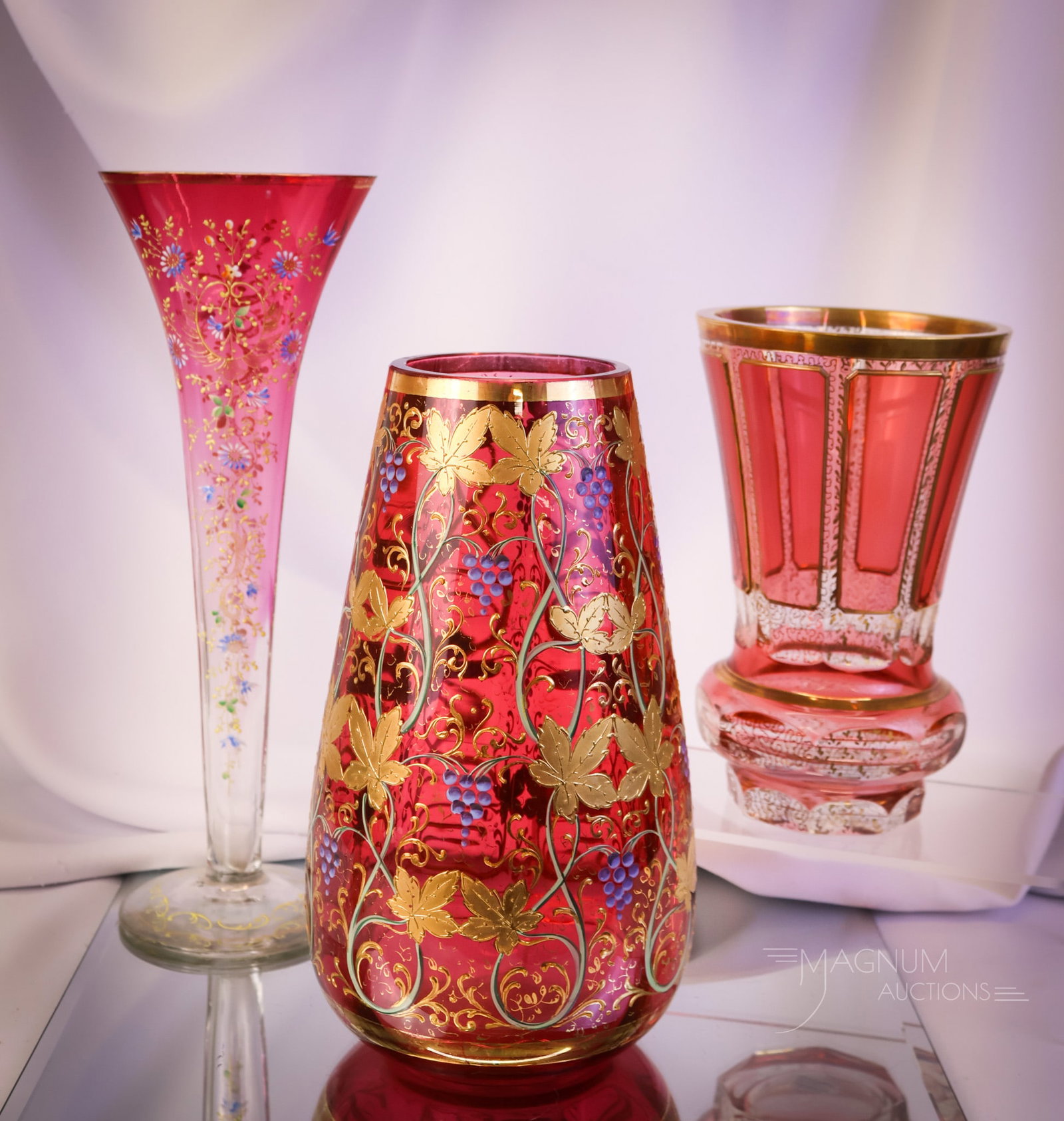 3 pc Lot Moser Cranberry Glass Vases: Three selections for your bidding pleasure. This lot has three desirable finds in Moser cranberry enameled and gilt glass. The first is a cabochon-decorated vase with gold. The second is gold enameled
