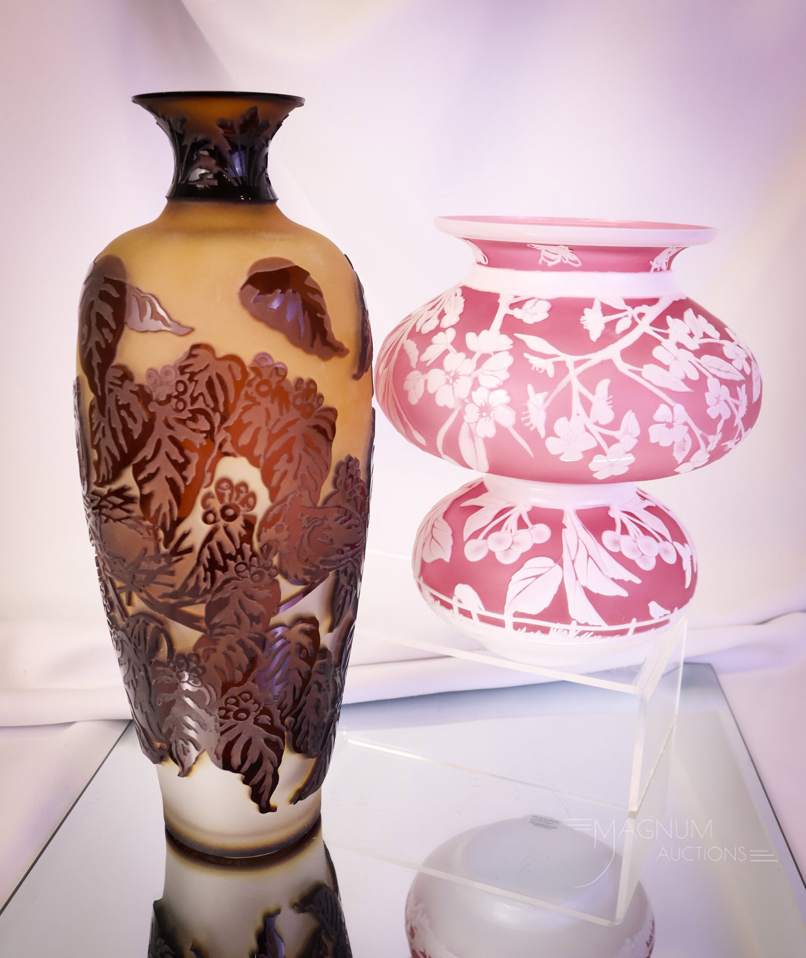 2 pc Lot Pilgrim Cameo Art Glass Vases: Two beautiful examples of cameo art glass. The first is a Chris Carpenter, "Queen Anne's Cherries" vase. The second is a Kelsey Murphy floral and leaf decorated vase, circa 1997. The tallest measures 