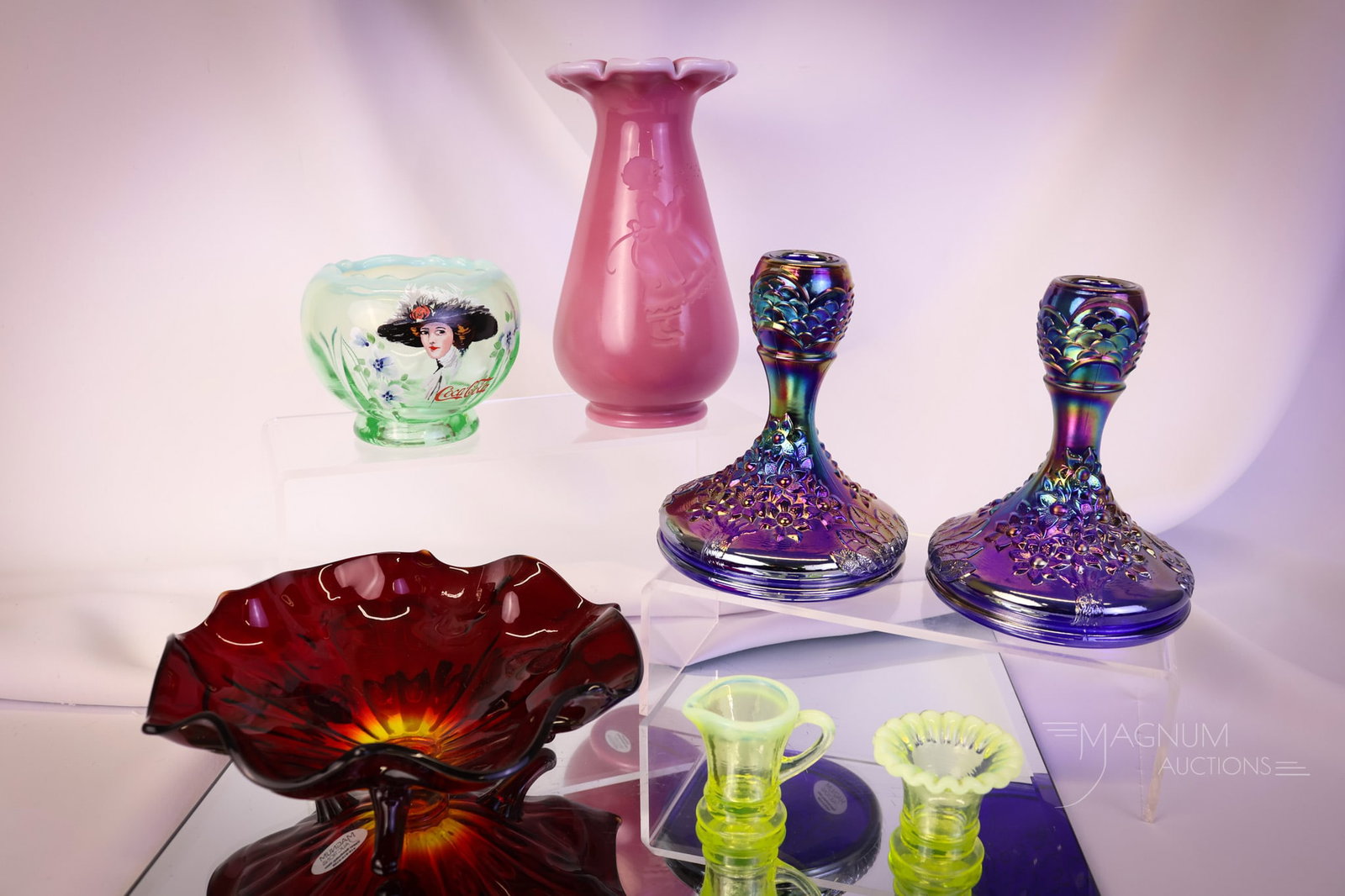 7 pc Lot Fenton Art Glass: Seven lucky finds in collection-enhancing Fenton Art Glass. The lot includes a rose quartz Intaglio vase, a Coca-Cola rose bowl, two topaz vaseline opalescent miniatures, a pair of carnival candlestic