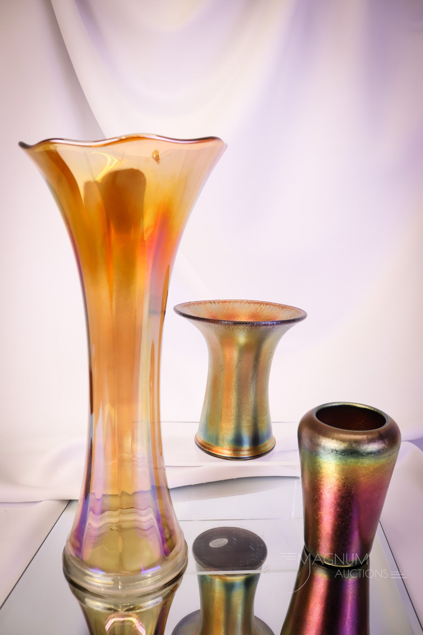 3 pc Lot Imperial Carnival Glass Vases: Three beautiful examples of Imperial carnival glass vases. The lot includes two amethyst stretch Jewel Line vases and one Smooth Panels marigold swung vase. The tallest measures 14" tall. SHIPPING NOT