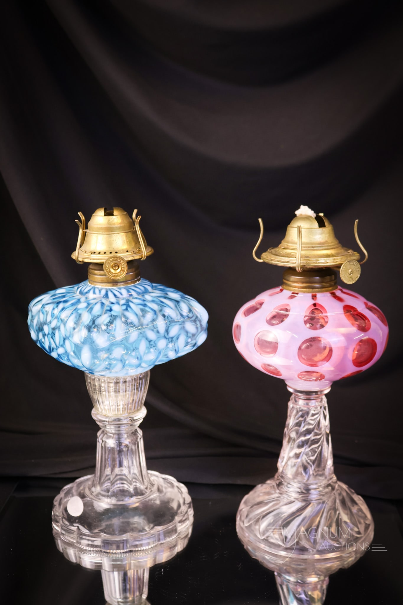 2 pc Lot Victorian Opalescent Glass Oil Lamps Cranberry & More: Two lovely examples of Victorian oil lamps in opalescent glass. The first is a cranberry Polka-Dot pattern with a clear twisted stem and foot. The second is a blue opal Christmas Snowflake. The talles