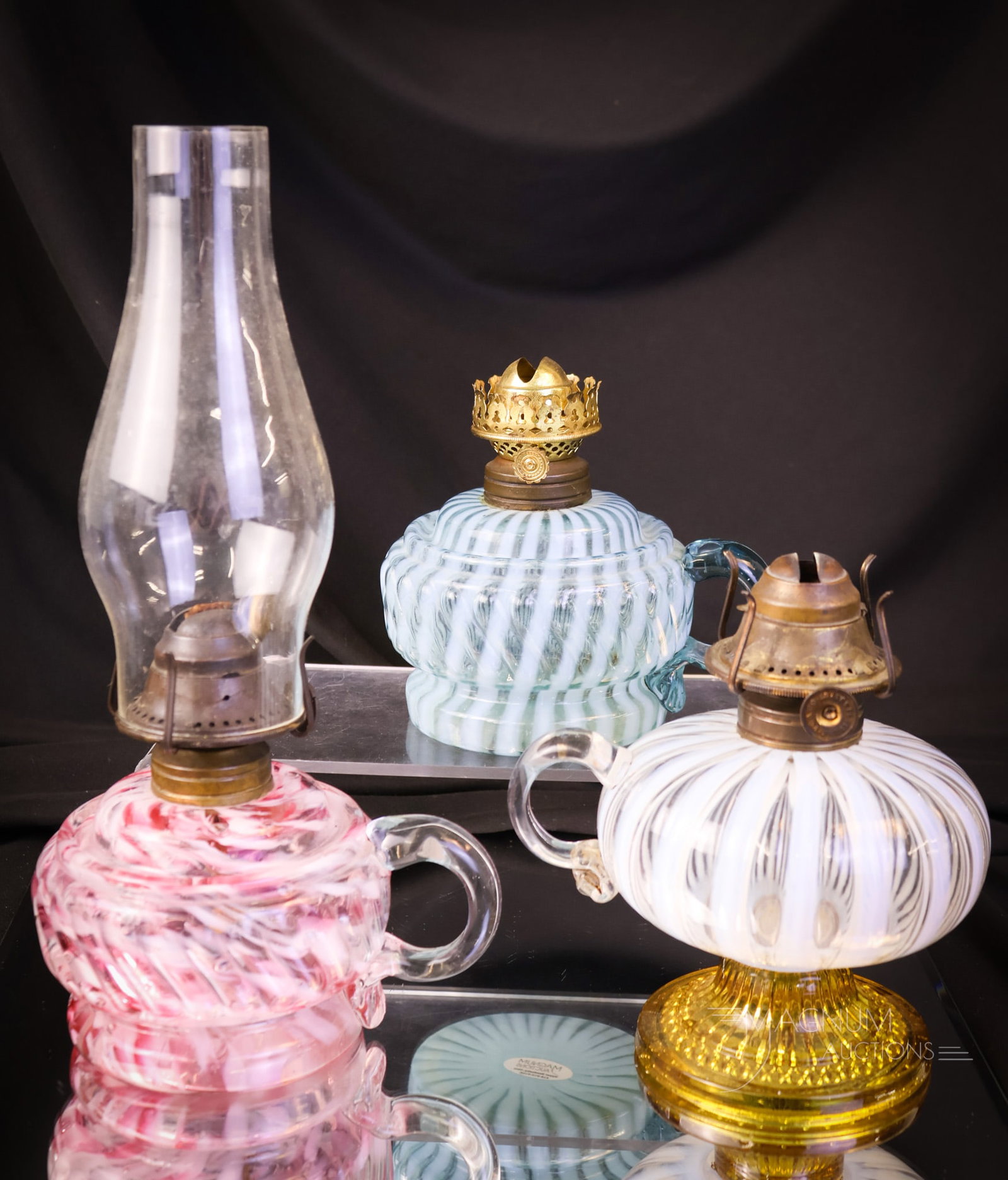 3 pc Lot Victorian Finger Oil Lamps: Three selections that are just plain nice. This lot includes a blue opal Markam Swirl pattern. A crystal opalescent Stripe example with an applied amber foot. Lastly, there is a pink and white spatter