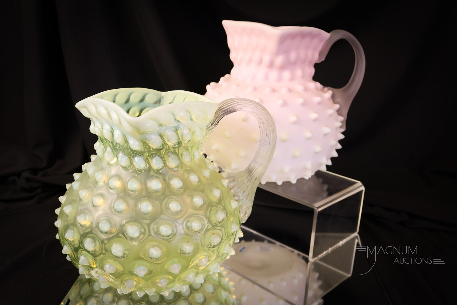 2 pc Lot Phoenix Burmese Vaseline Uranium Water Pitchers: Two desirable finds in Victorian water pitchers are attributed to Phoenix glass. The first is a burmese glass. The second is a vaseline opalescent Hobnail pattern. Both pitchers glow brightly under bl