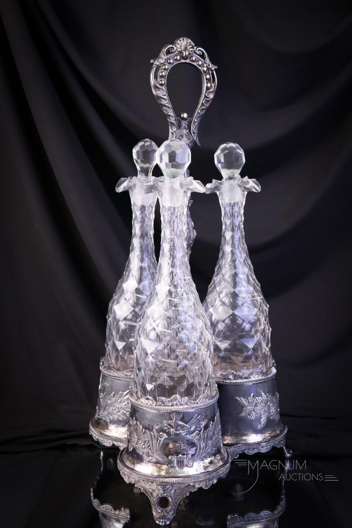 Attributed to Dorflinger Early Cut Glass Tantalus Decanter Silverplate Set: A showy early cut glass tantalus set in silverplate holder. This set features three honeycomb cut decanters set in an ornate silverplate holder. The complete set measures 19" tall. SHIPPING NOTICE: If