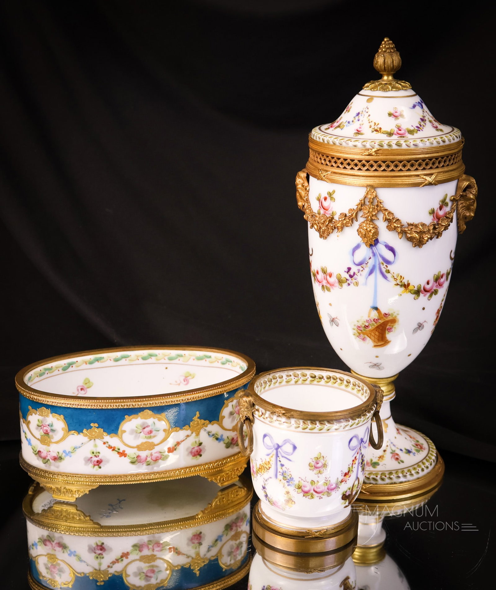3 pc Bronze Mounted Sevres Porcelain: Three distinct finds in bronze-mounted Sevres porcelain. The first item is an urn with a lid and decorated in florals and features ram head-adorned handles. The second is a pin dish in blue with flora