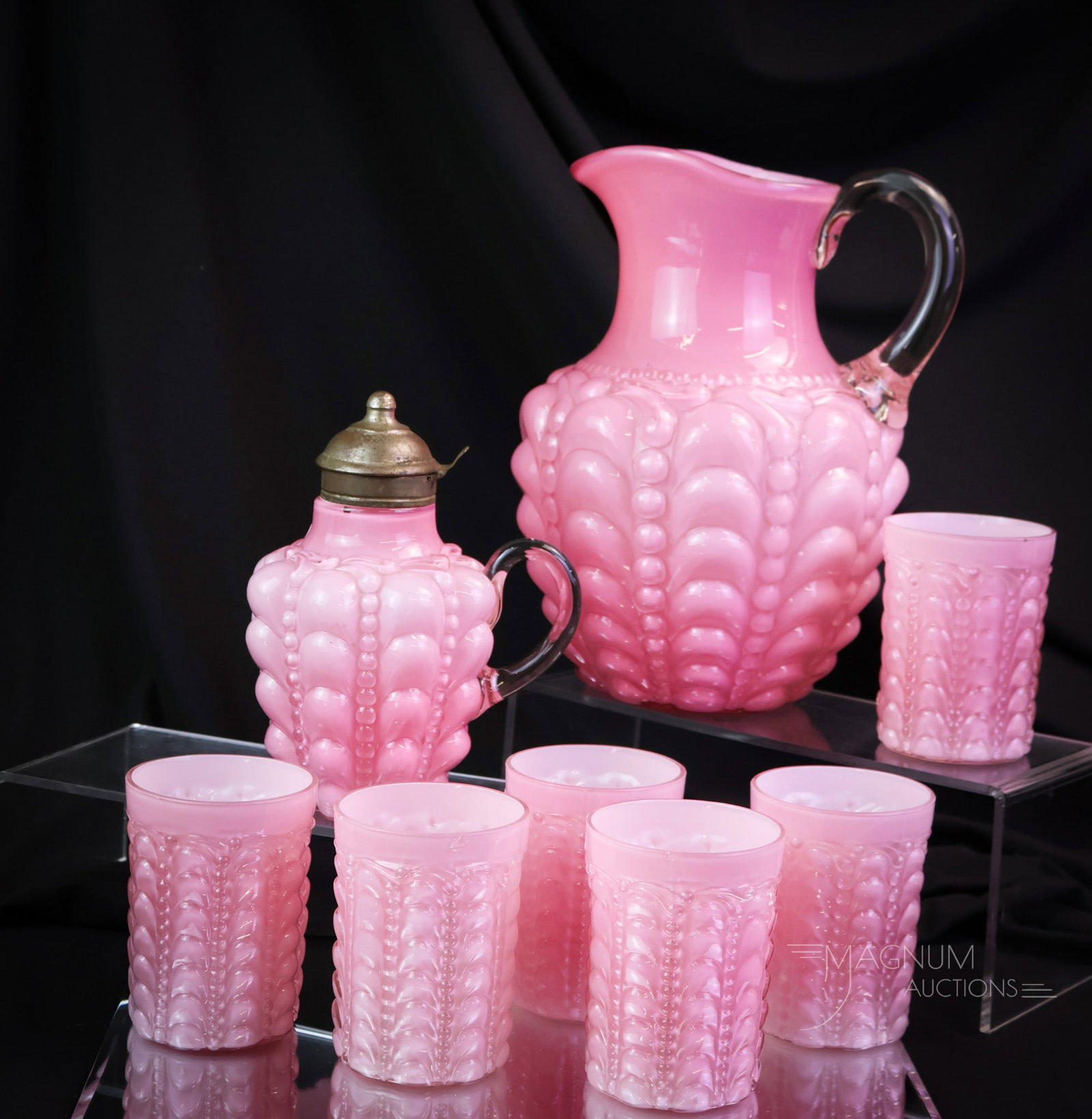 8 pc Lot Consolidated Glass Pink Cased Guttate Water Set & Syrup: A generous offering of eight pieces of Consolidated glass in the Guttate pattern. There is a seven-piece water set along with a bonus of a syrup pitcher. The tallest measures 9 3/4". One tumbler exhib