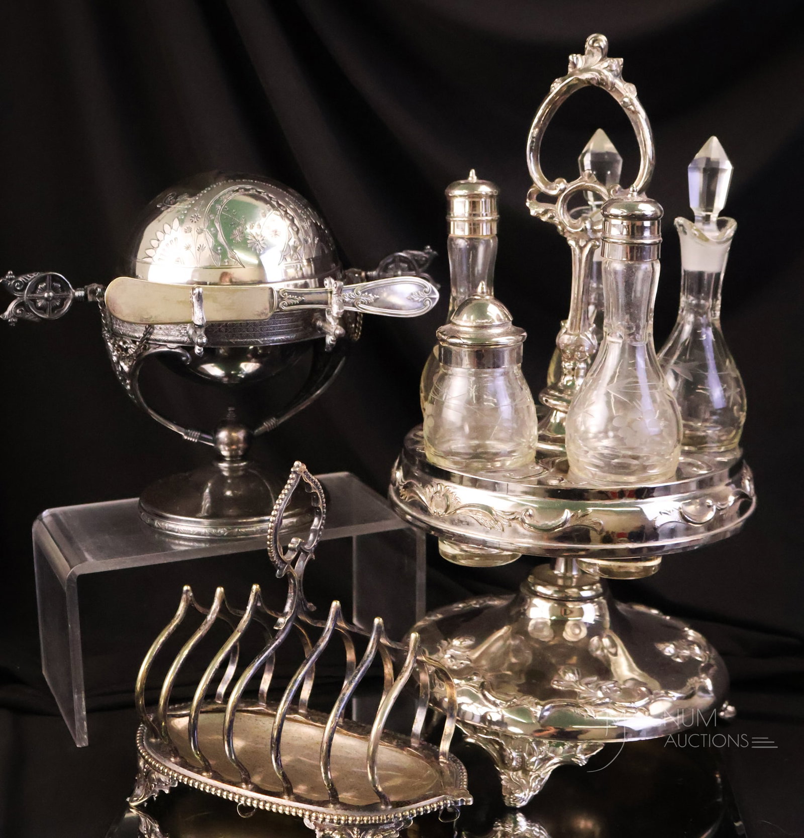 3 pc Lot Antique Victorian & More Silverplate: Three selections in Victorian and more silverplate that are sure to please. The lot includes a castor with five condiment bottles, a toast rack, and lastly, a mechanical pedestal engraved butter dish