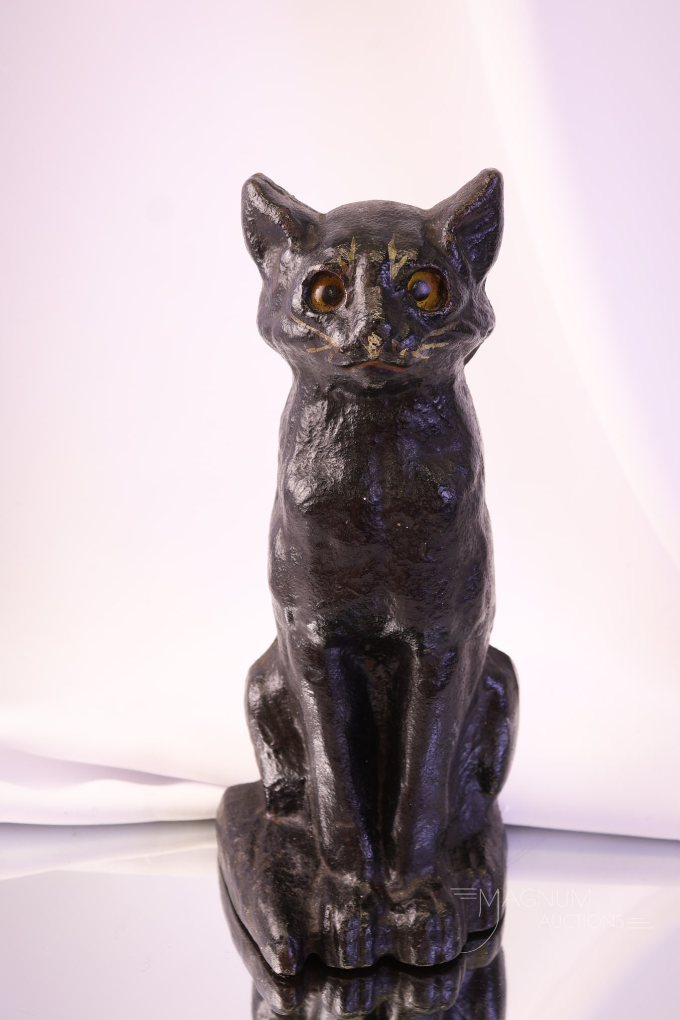 Antique Cast Iron Black Cat Doorstop: A charming antique black cat cast iron doorstop. The cat features glass eyes and detailed painting. This fine early piece measures 10" tall and 4 1/2" wide.