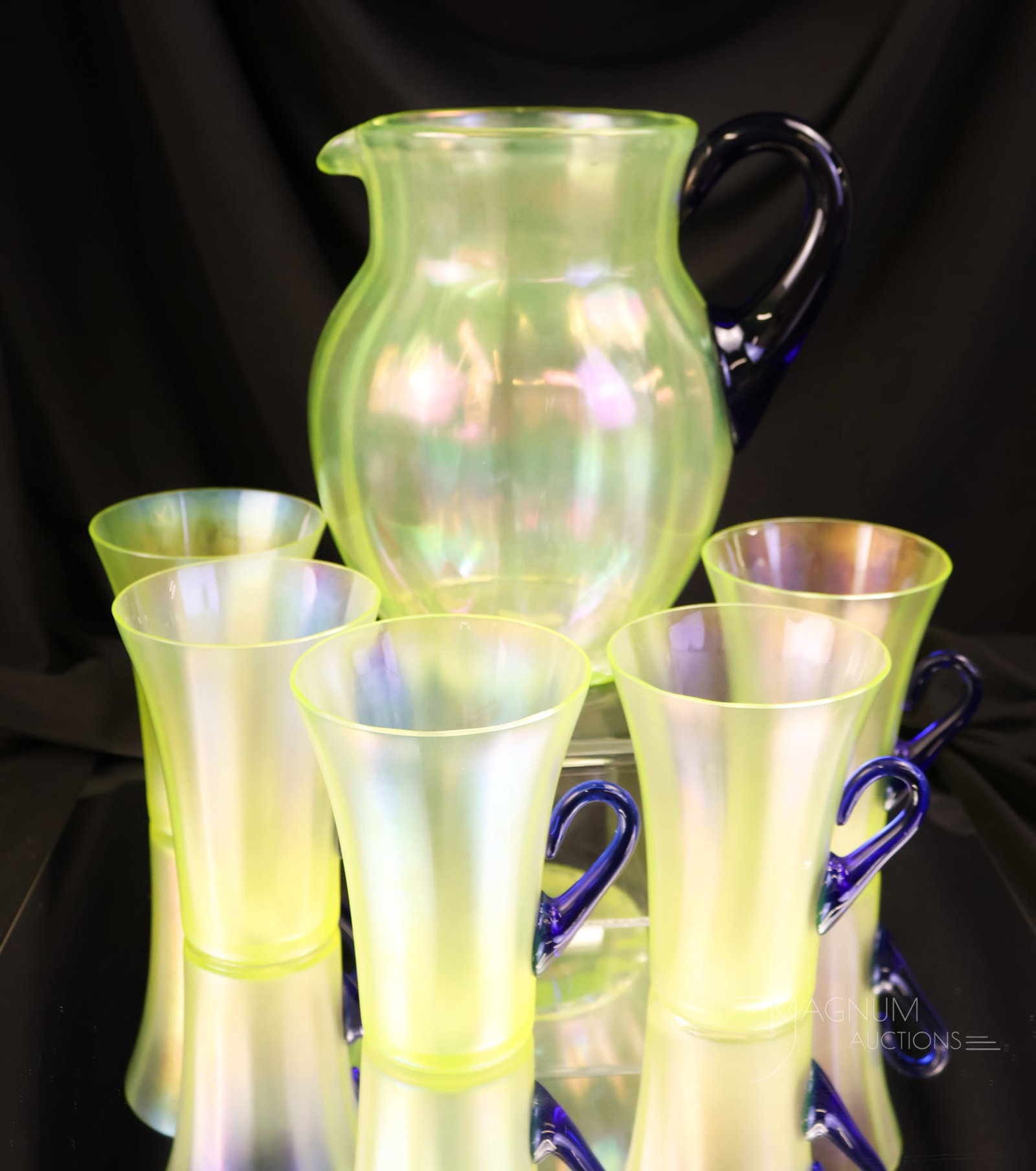 Fenton Topaz Vaseline Uranium Stretch Glass & Cobalt Water Set: A beautiful find in 1930s Fenton Stretch glass. This is a six-piece water set with cobalt handles. This uranium-rich offering glows like no tomorrow. The tallest measures 8". One cup exhibits a rim fl