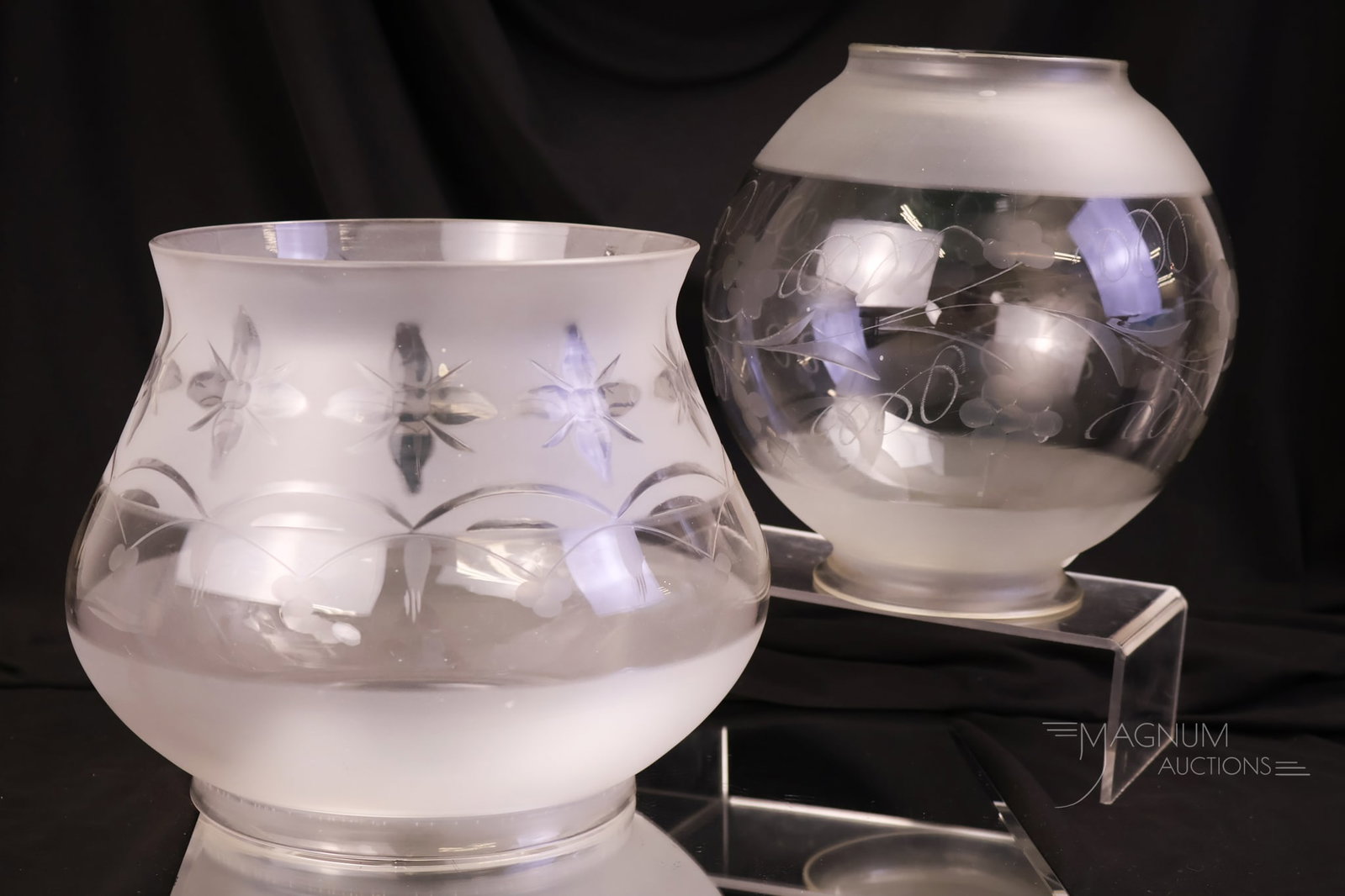 2 pc Lot Astral Glass Lamp Shades: A two-piece lot Astral lamp shades. The first is a ball form with a frosted and etched design of florals and leaves. This one measures 8" tall, 7 1/2" wide, and has a fitter rim that measures 4 1/4". 