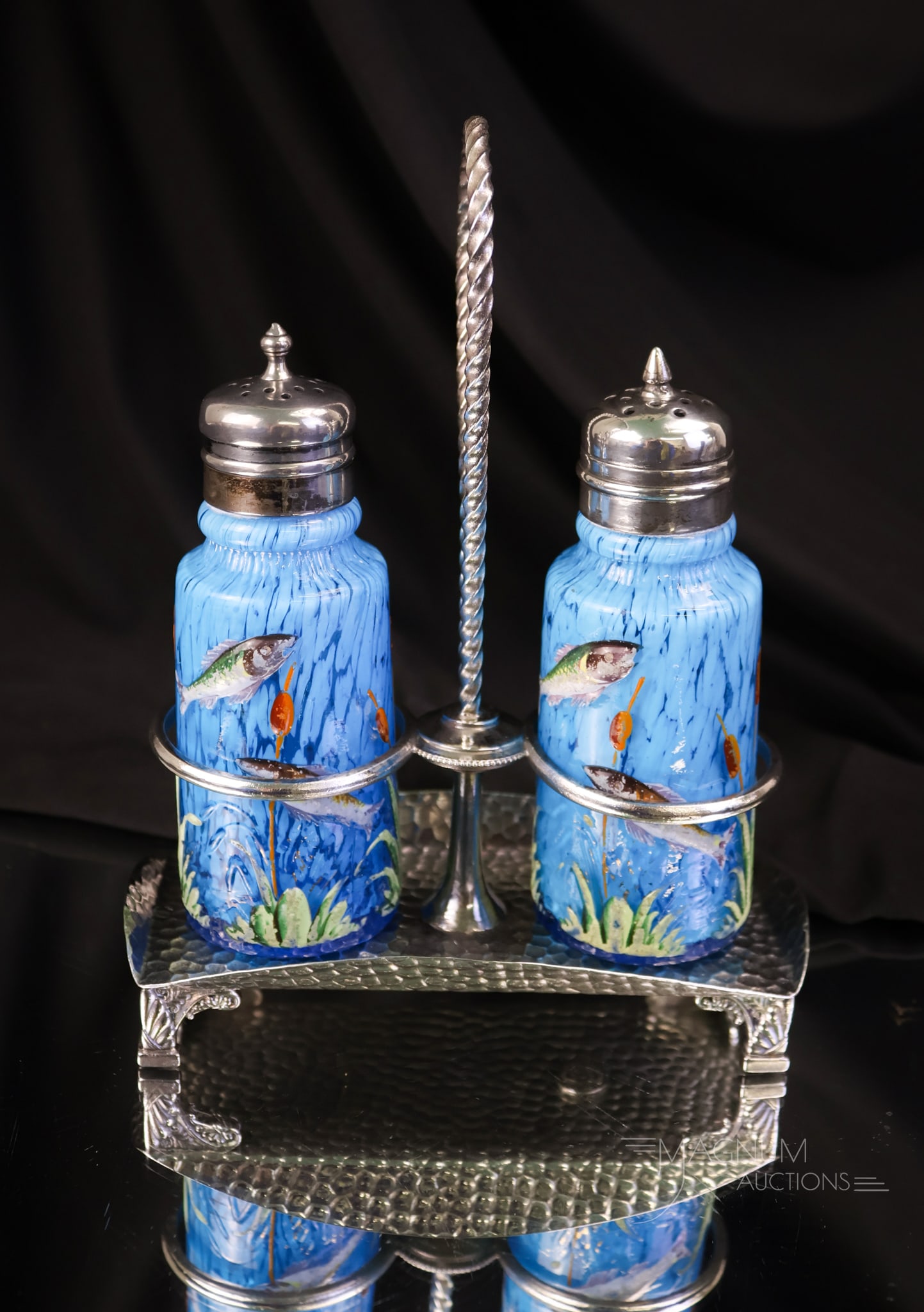 Pair Victorian Blue Fish Pond Cased Spatter Salt Shakers in Silverplate: A highly prized pair of Victorian blue-cased spatter glass salt shakers in the fish pond pattern. These cylinder-form shakers have snakes, fish, and cattails in relief on the body. This pair is set in