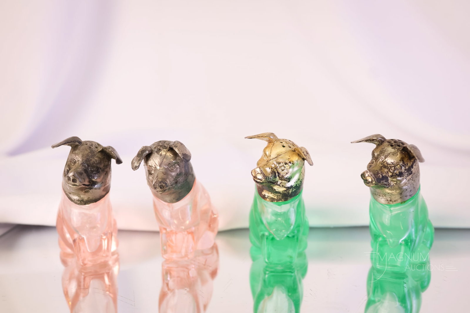 4 pc Lot Figural Pig Antique Glass Salt Shakers: Four portly little pig figural glass salt shakers. This lot includes a pair of pink and a pair of teal-green uranium-rich pigs. Each measures 2 1/2" tall.