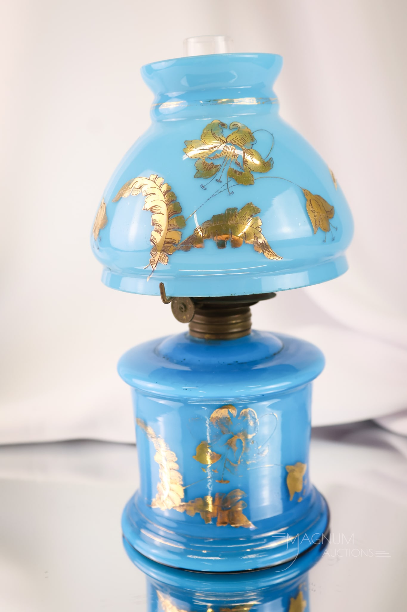 Victorian Blue Cased Gilt Glass Miniature Oil Lamp: A beautiful find in a Victorian miniature oil lamp. This one is in deep blue cased glass with gilt floral decoration on the shade and the base. The lamp measures 7 3/4" tall.