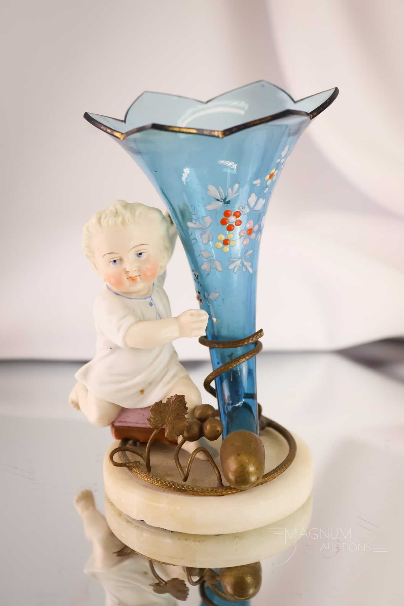 Victorian Bisque Figural Glass Enamelled Bud Vase: A charming find and a whimsical piece of bisque Victoriana. This is a baby fitted on a marble base holding a blue enamelled glass cornucopia-shaped bud vase. The piece measures 4 1/2" tall and 3 1/2" 