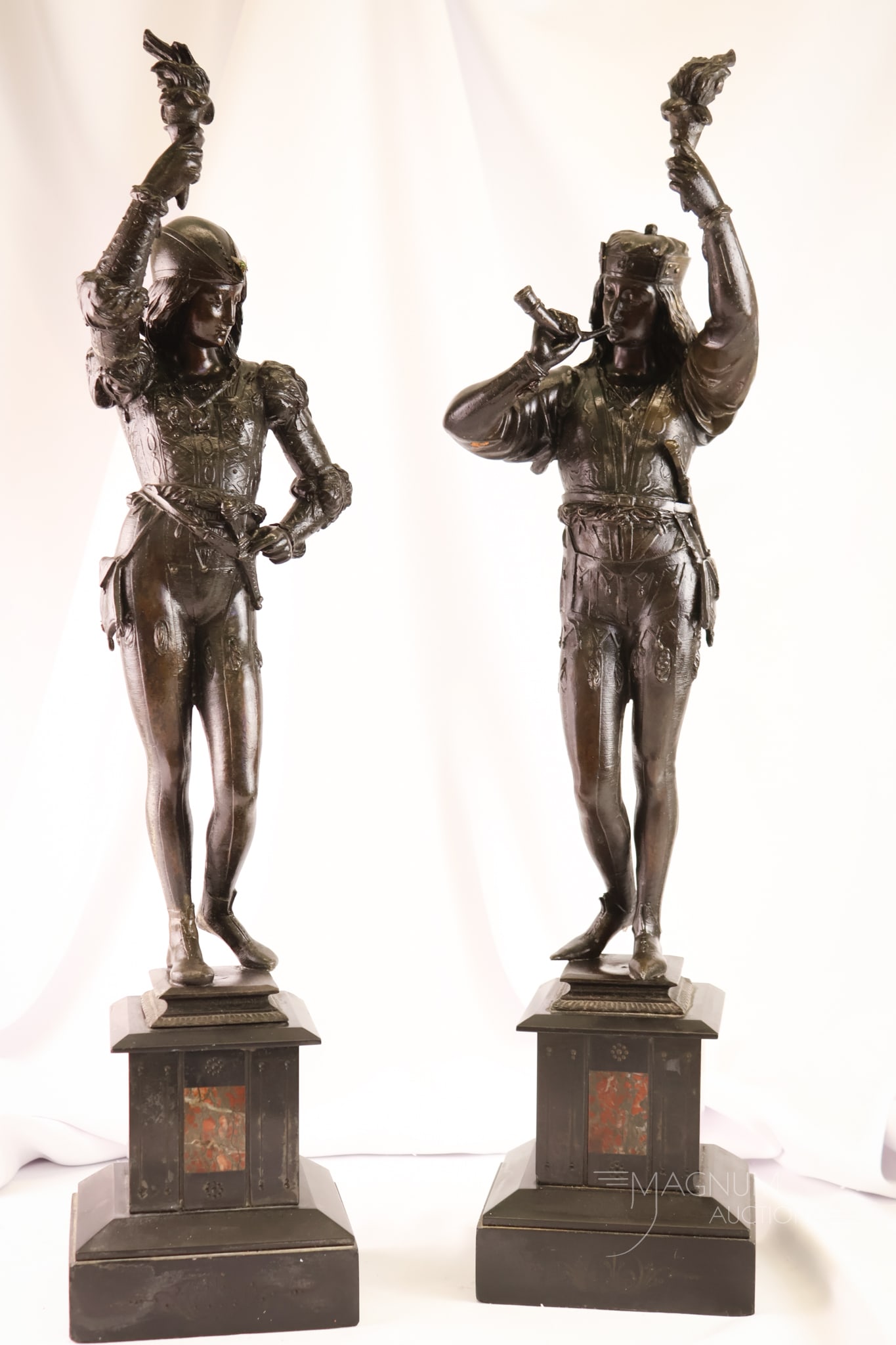 Matched Pair 25" Art Deco Spelter and Marble Male Statues: A select offering of a matched pair of 25" tall Art Deco-period statues on marble bases. Each depicts a male figure in Renaissance attire holding torches. Each figure with bronze finish and exquisite 