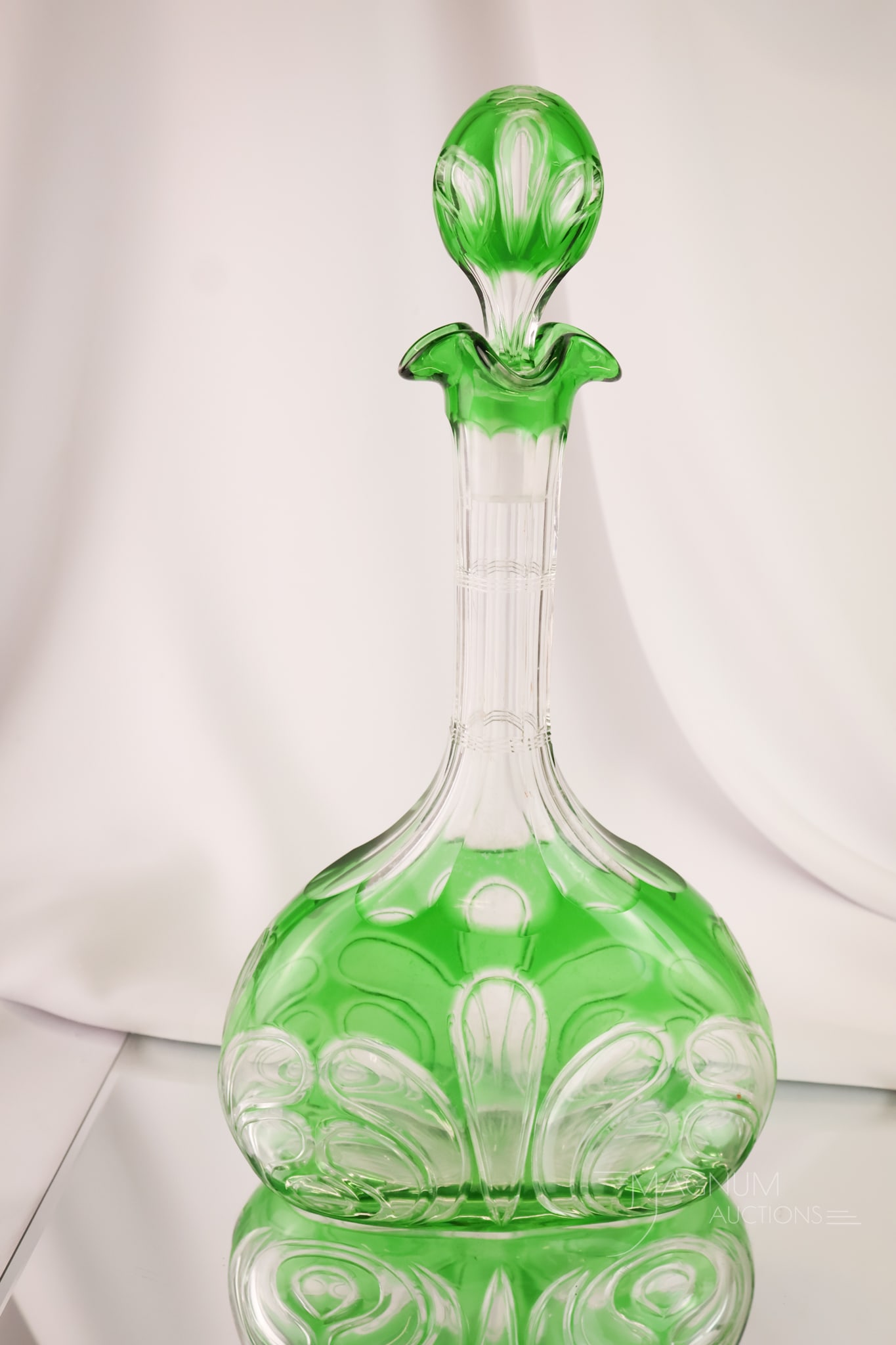 Stevens & Williams Enmerald Green 13 1/2" Cut Glass Decanter: A beautiful find in Stevens & Williams cut glass. This is an emerald green cut-to-clear decanter in a plume design. The piece features a matching stopper. The decanter measures 13 1/2" tall and 6 1/2"