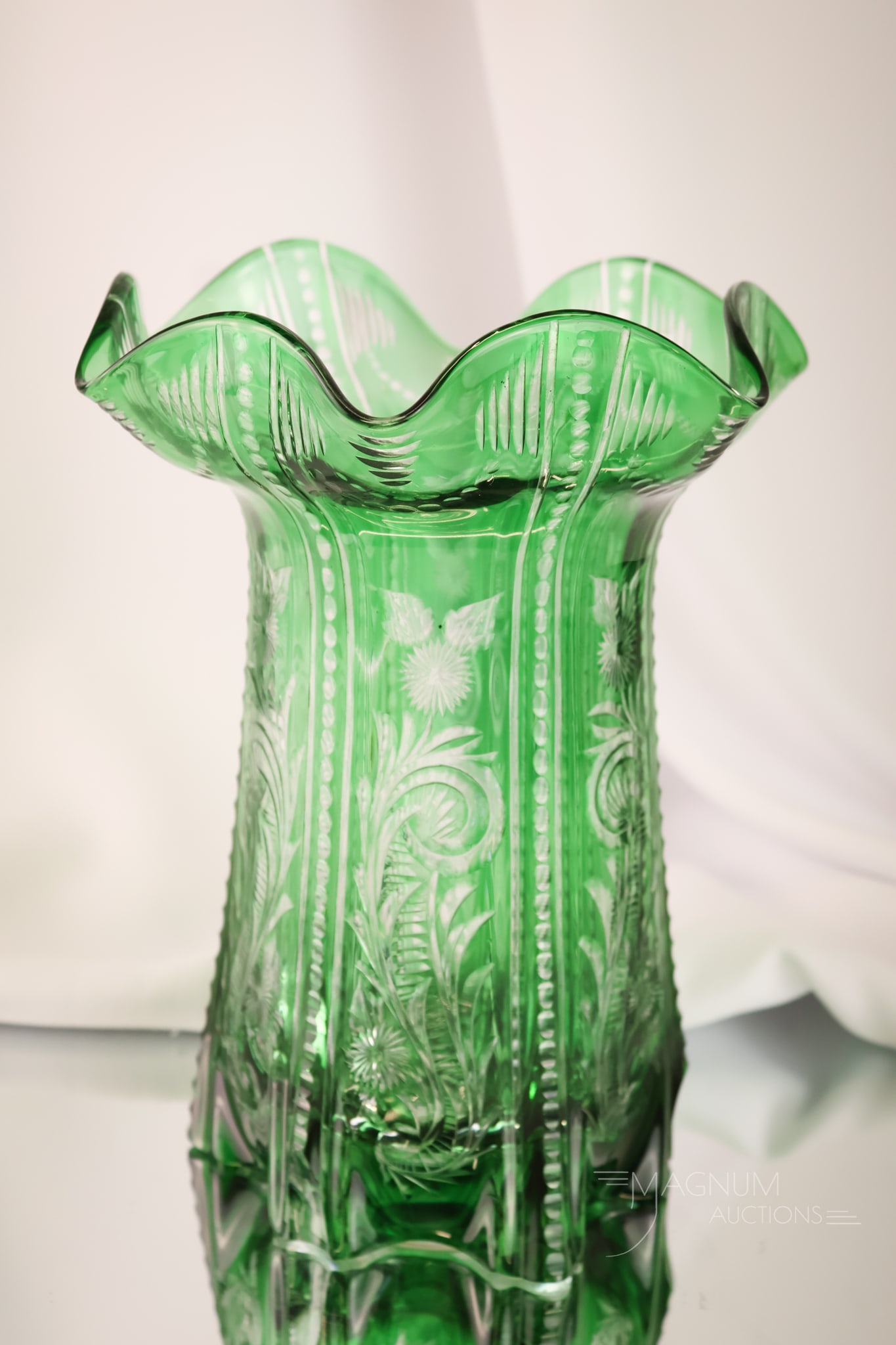 Stevens & Williams Green Cut Glass Vase: A fine offering in Stevens & Williams emerald green cut to clear glass. This vase has a most unusual form. It has an all-over engraved floral design. The vase measures 9 1/2" tall.
