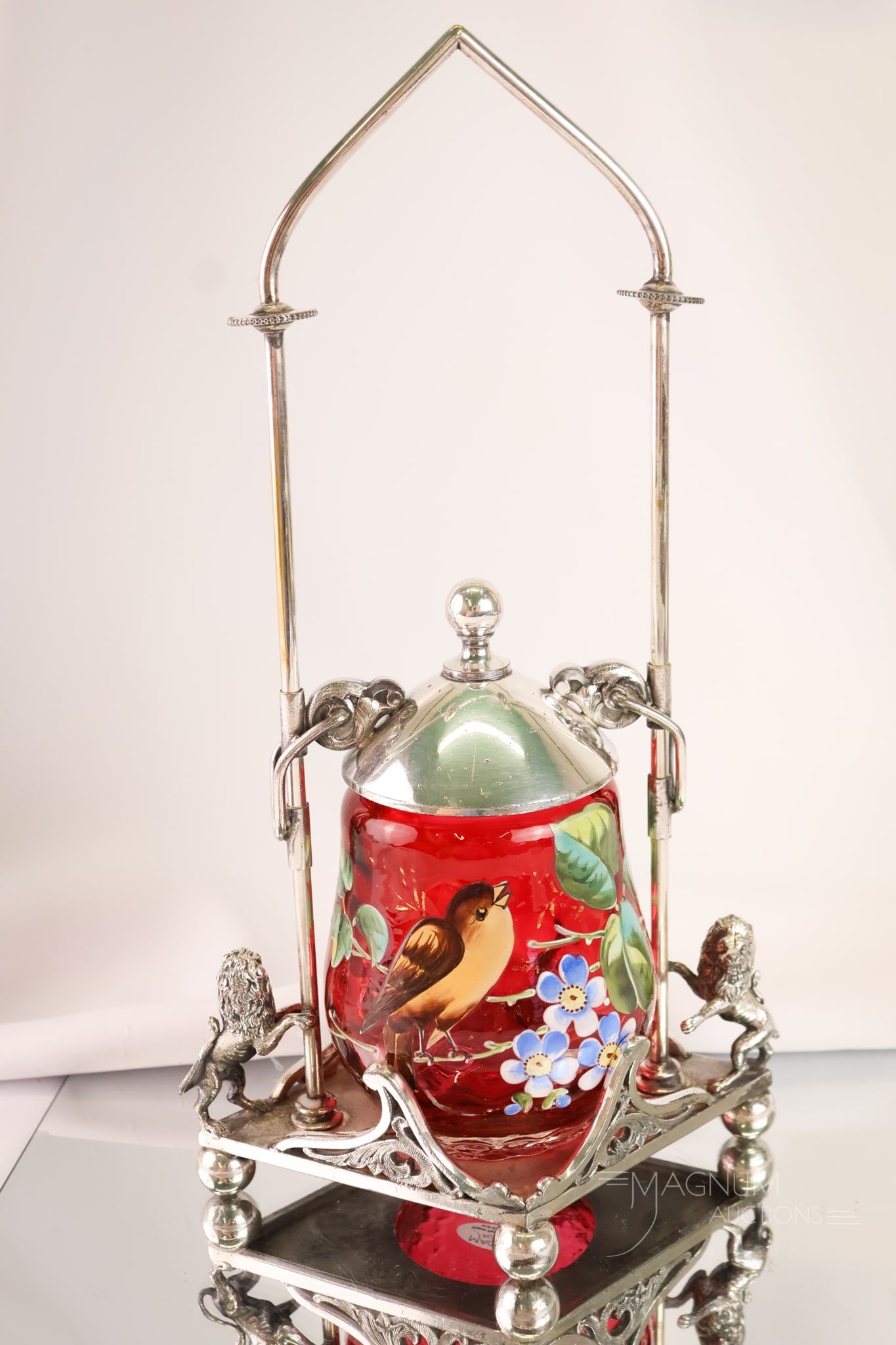 Meriden Silverplate Lion Adorned Cranberry Enamelled Glass Pickle Castor: A wonderful figural lion Victorian pickle castor. This castor frame is large and has a mechanical sliding lid on the handle. The jar is cranberry-enamelled with florals. The castor measures 12 1/2" ta