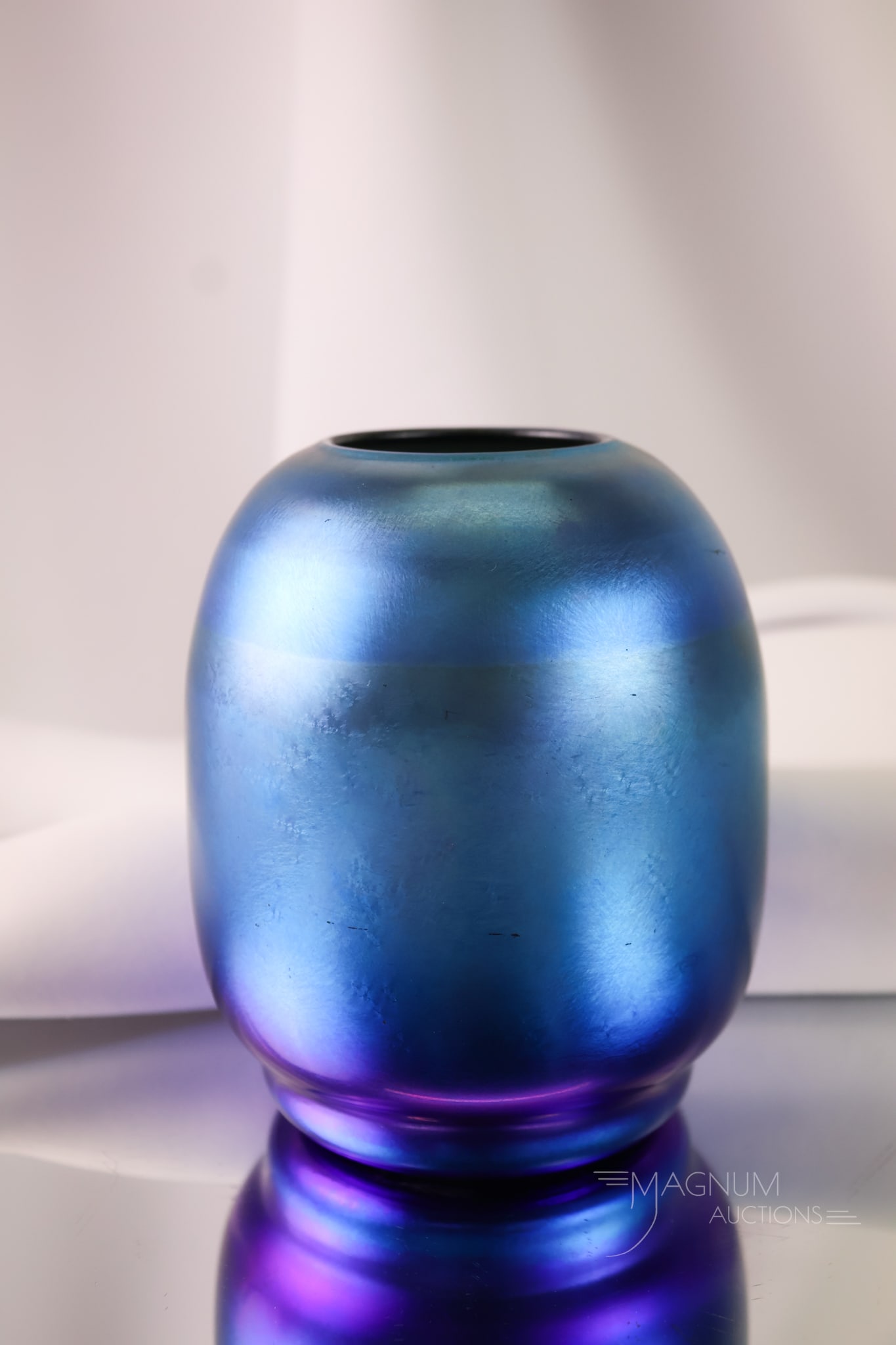 Signed Durand Blue Iridescent Art Glass Vase: A striking example of a signed Durand blue iridescent glass vase in a squat form. The vase measures 4 1/2" tall and 4" wide.