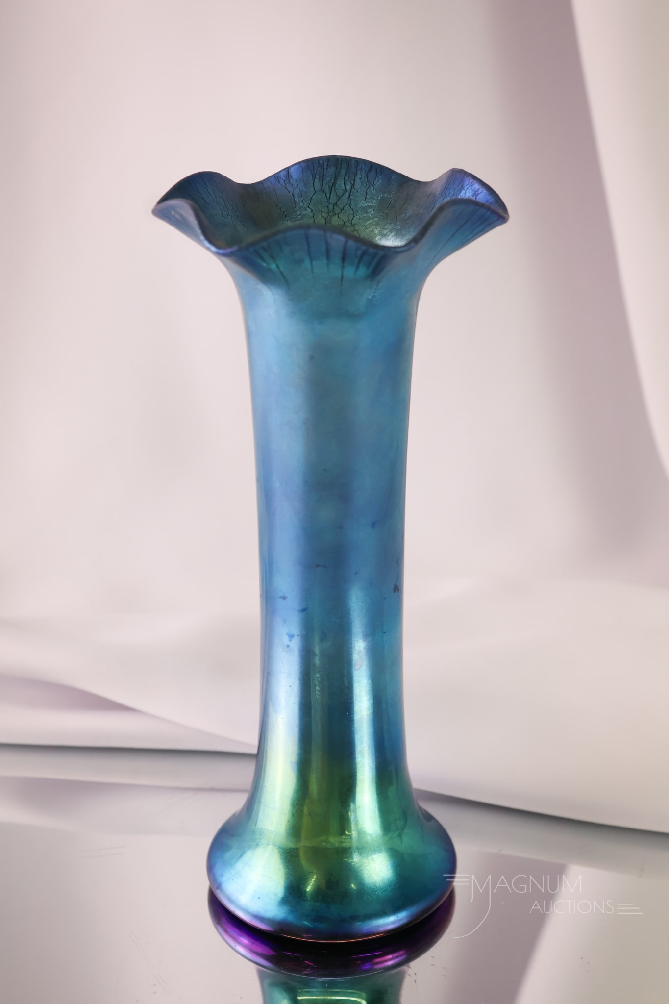 Signed Steuben Blue Aurene Art Glass Vase: A striking Steuben blue aurene ruffled tall art glass vase. This vase has an onion skin finish on the rim. It is signed "Aurene 355." The vase measures 8 1/2" tall and 3 3/4" wide.