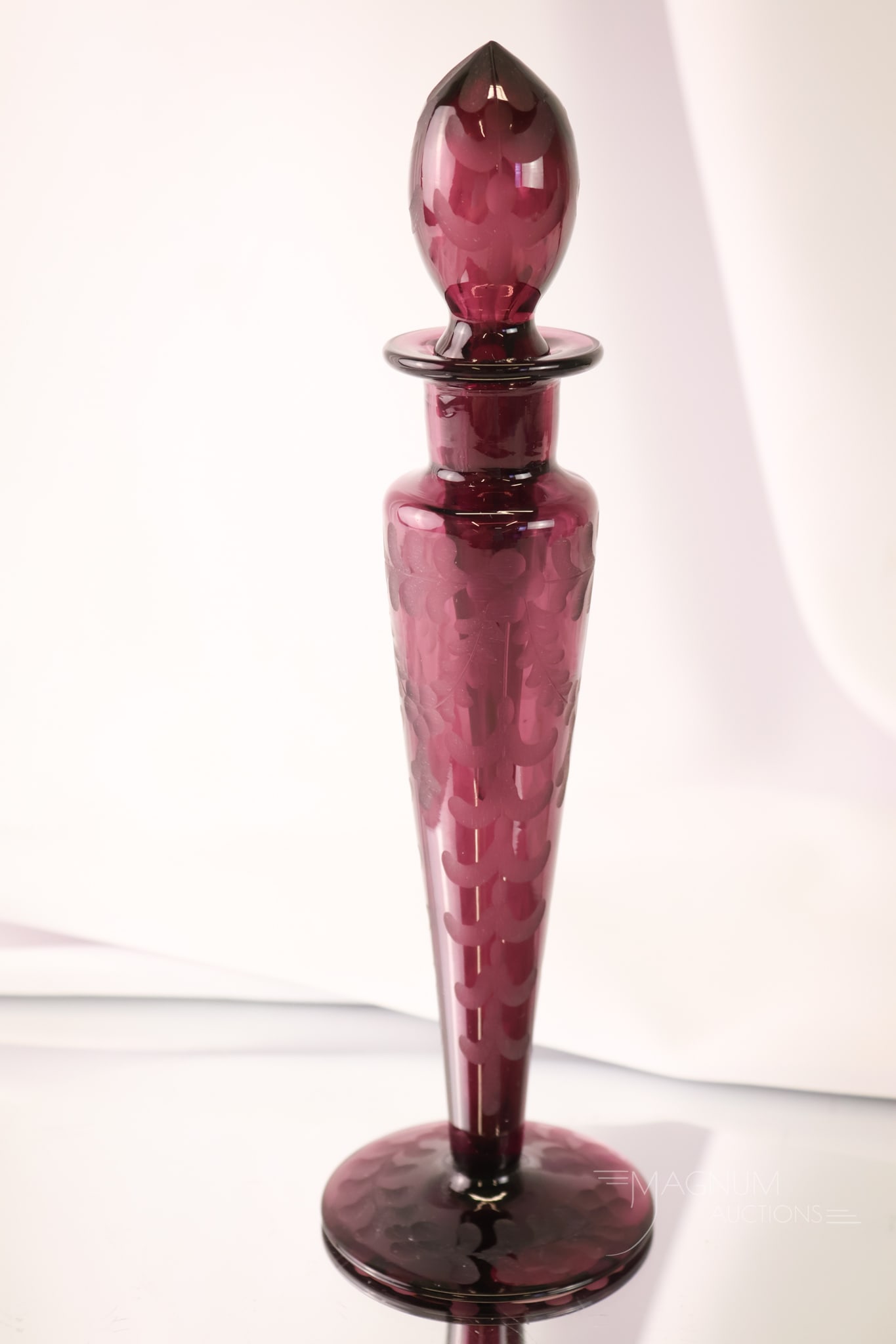 Steuben Attributed Engraved Amethyst Glass Perfume Bottle: A beautiful find attributed to Steuben. This perfume is engraved with a floral motif. The bottle is complete with its original matching stopper. The perfume measures 10" tall.