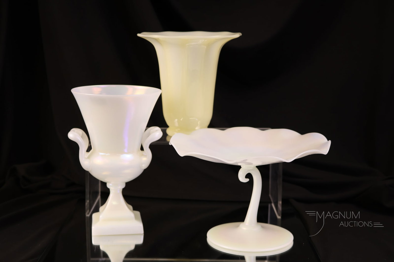 3 pc Lot Steuben Ivrene Art Glass: Three selections of Steuben Ivrene art glass. The lot offers a stemmed compote. A handled urn. Lastly, there is an ivory shade vase that's rich in uranium content. The tallest measures 6 1/2".