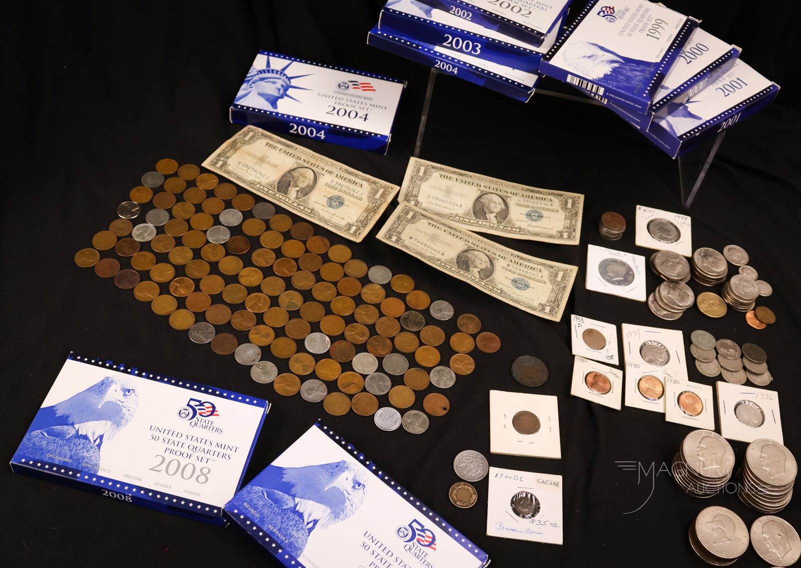 A Generous Collection of Currency: For your bidding pleasure, here is a generous collection of currency. This lot has 11 $1.00 coins. 17 half dollars. 7 nickels, 2 dimes, 2 pennies, 1 quarter, and one Roman coin. There is an 1881 India