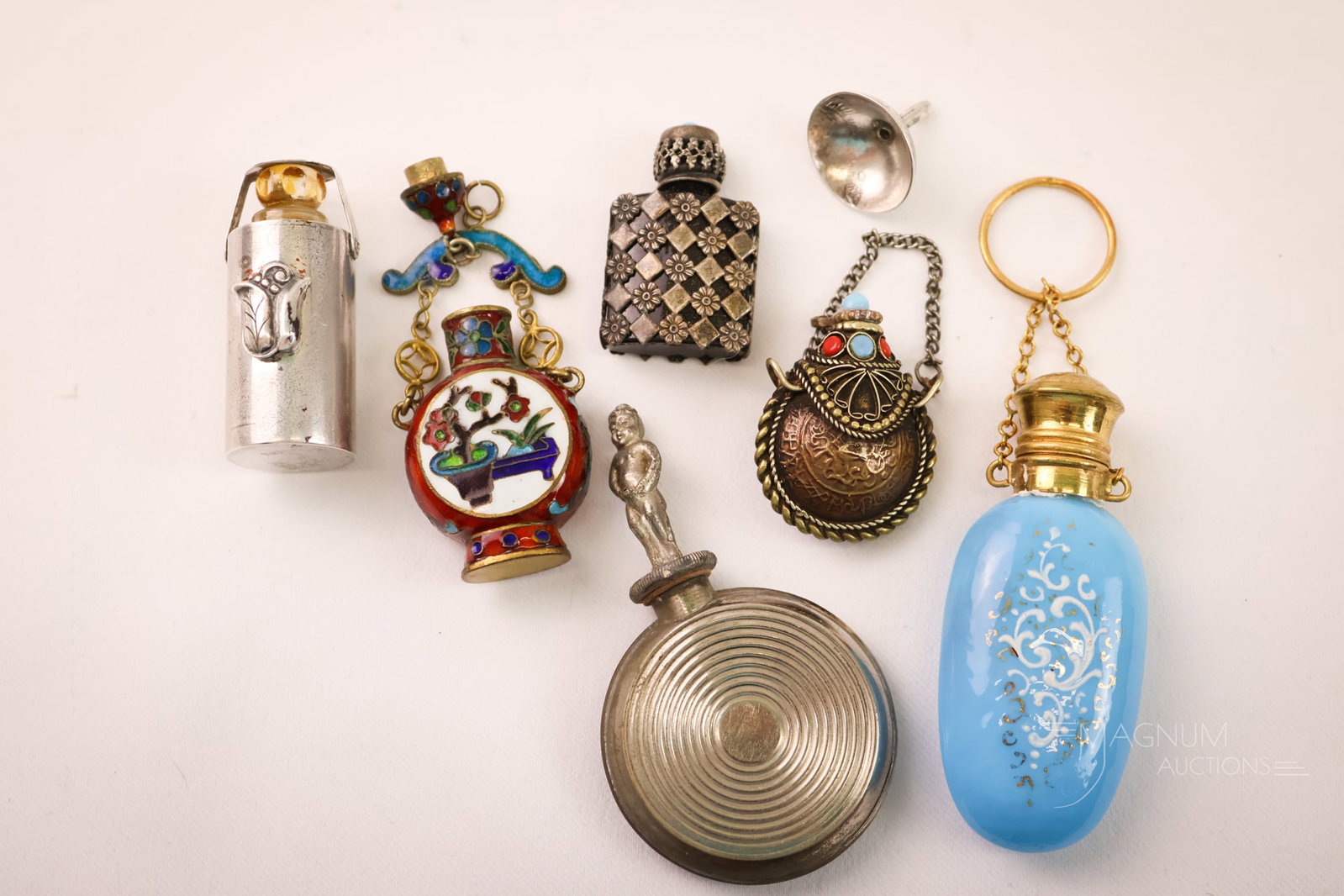 Collection of Antique Victorian & More Perfume Bottles: A seven-piece lot of collectible perfume-related items. This lot includes a Victorian blue opaline enamelled glass perfume with a chain and ring for your finger. There is a silverplate perfume with a 