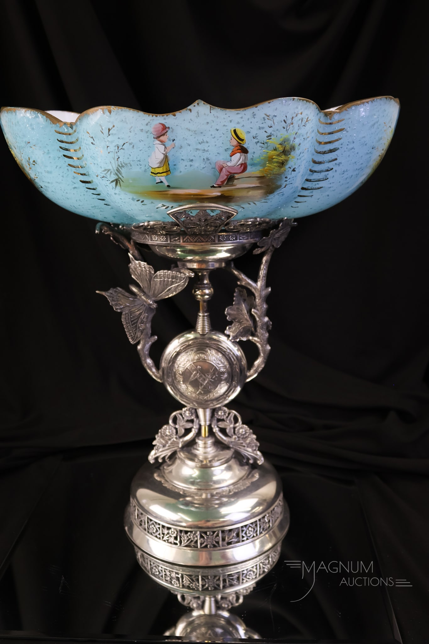 Derby Silverplate Spangle Enamelled Glass Brides Bowl Centerpiece: A beautiful signed Derby silverplate pedestal Bride's Bowl centerpiece. This piece showcases a spangle-cased glass bowl. The bowl is enamelled with children and flowers. The frame features a full wing