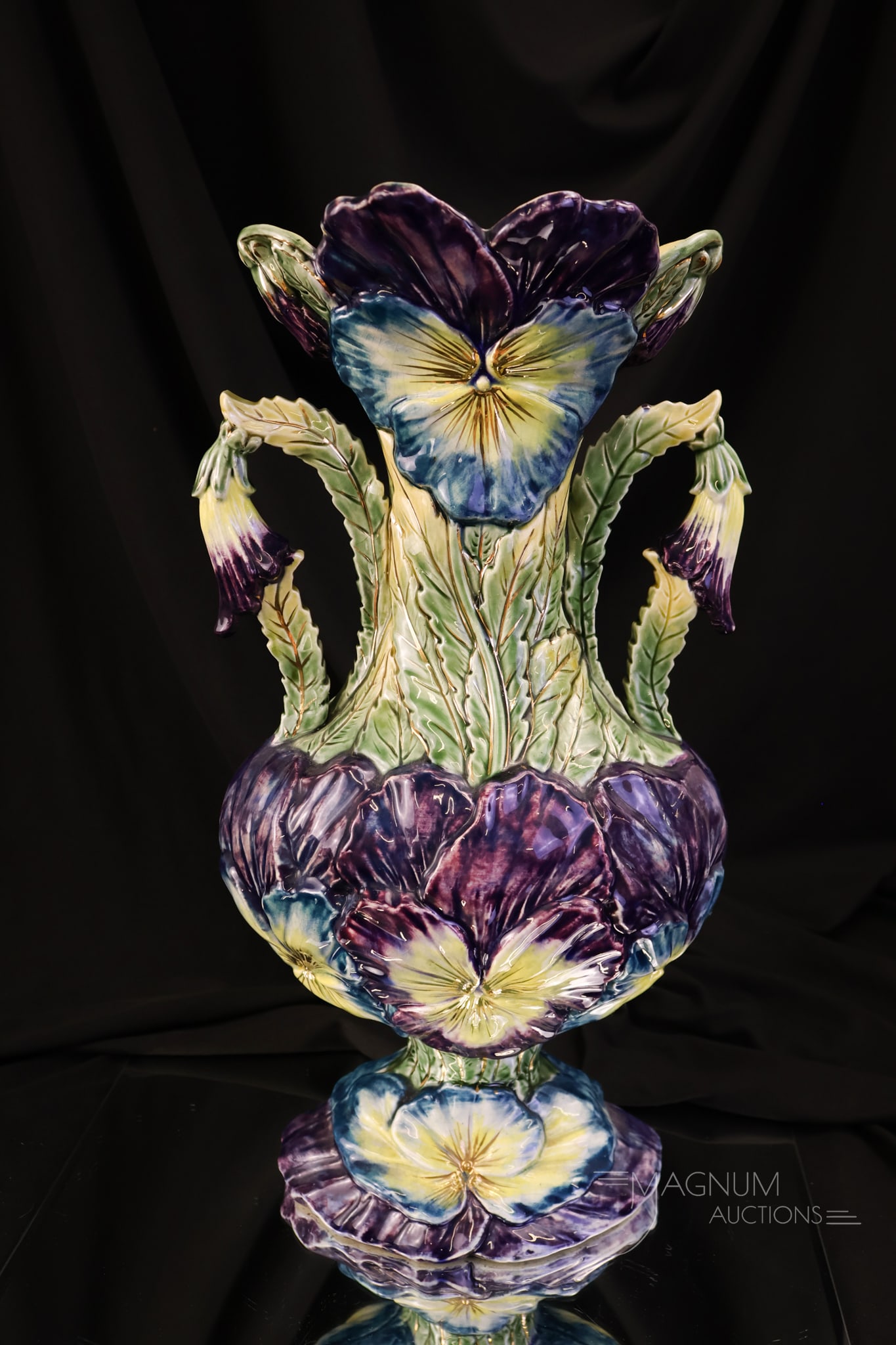 Victorian Majolica Pansy 14 1/4" Vase: A beautiful Victorian Majolica vase featuring colorful purple and blue pansy flowers. The vase features handles. The vase measures 14 1/4" tall and 8" wide. The vase exhibits crazing.