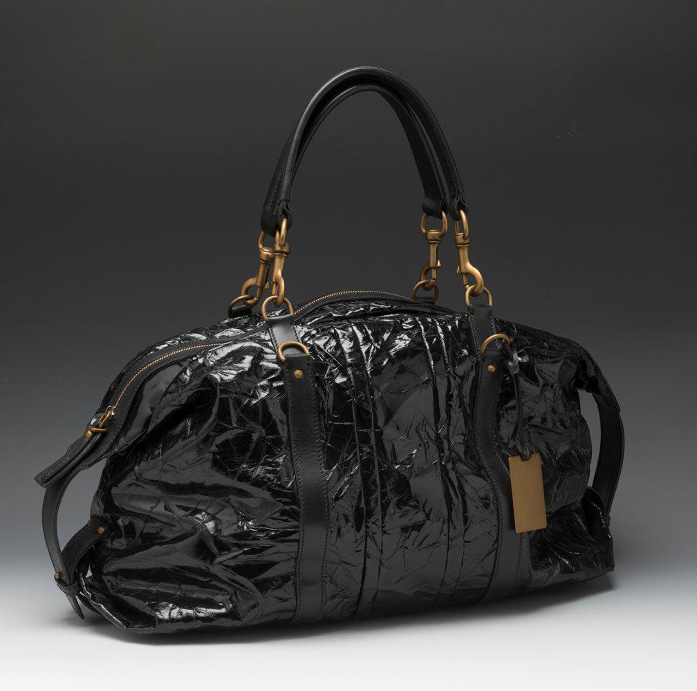 ESCADA. Black patent leather handbag with black leather details. Short non-adjustable handles: ESCADA. Black patent leather handbag with black leather details. Short non-adjustable handles connected to the body of the bag by golden carabiners. Zipper closure. Brown cotton lining. Slight marks o
