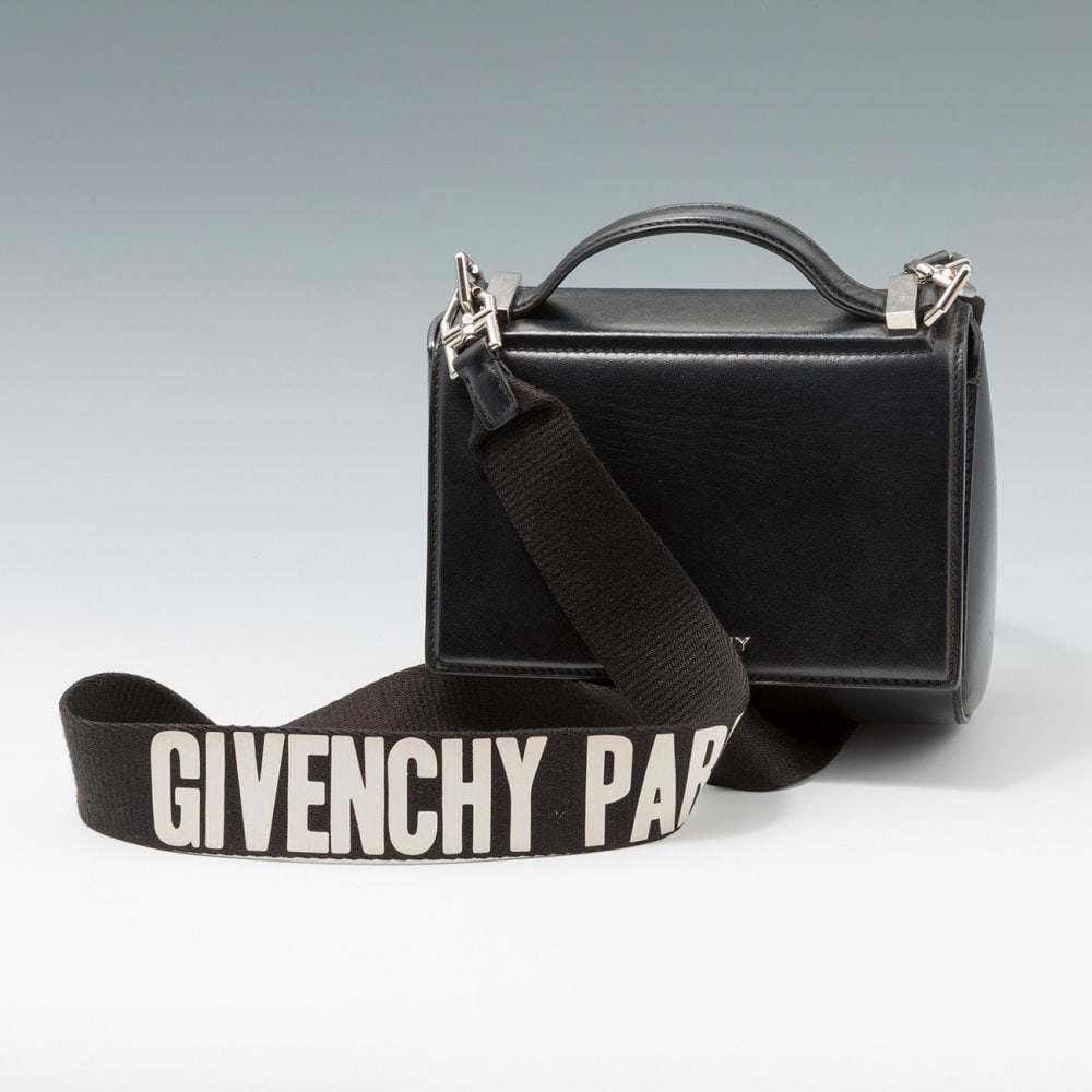 GIVENCHY. Pandora handbag. In black leather. Semi-rigid structure with front flap. Short top handle: GIVENCHY. Pandora handbag. In black leather. Semi-rigid structure with front flap. Short top handle and shoulder strap in cotton with white lettering. Silver hardware. With dust bag. Measurements: 18