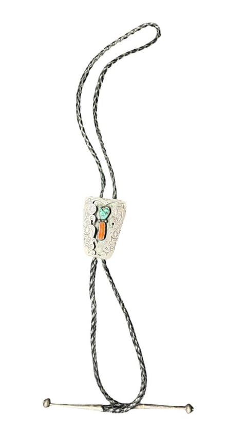 Vintage Sterling Silver Southwest Bolo Tie: This vintage sterling silver bolo tie has the classic Western style. The sterling silver slide features turquoise and red coral, framed by stamped borders. The braided leather cord is supple, and show