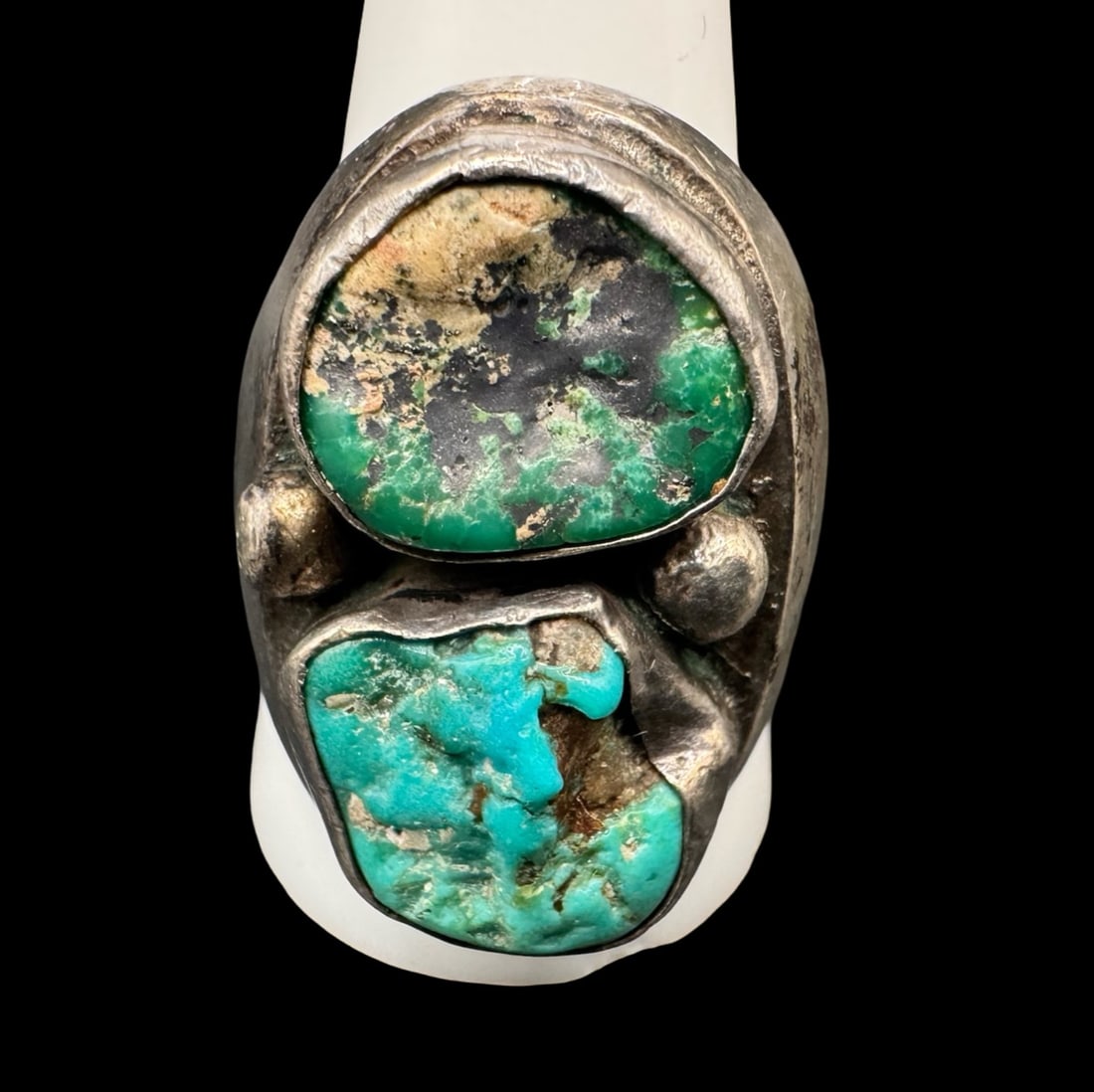 Sterling Silver Navajo Two Tone Turquoise Ring: This sterling silver Navajo ring features a deep green turquoise top stone, along with a classic bright turquoise bottom stone. There are also two raindrops on the flanks. There is an illegible design