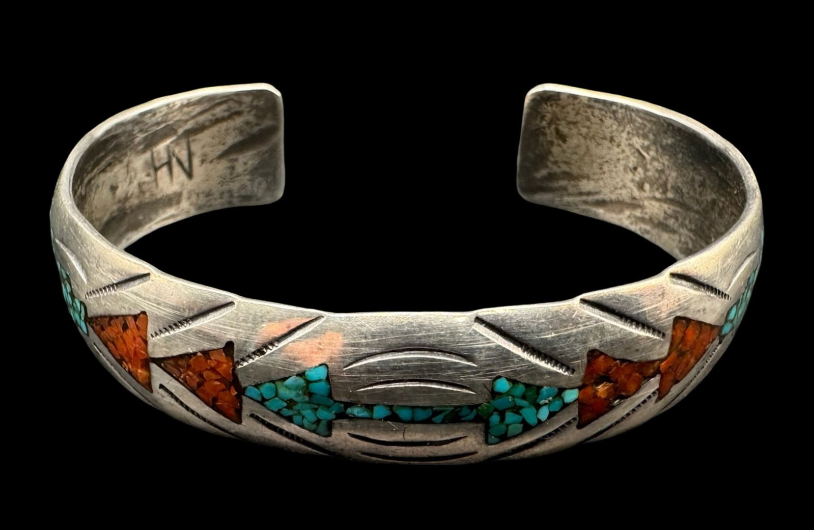 Sterling Silver Hoskie Nez Navajo Cuff: This mid-century sterling silver Navajo cuff features hand-shaped borders, geometric details, and dynamic chisel work. The center has an alternating geometric mosaic pattern filled with crushed or “