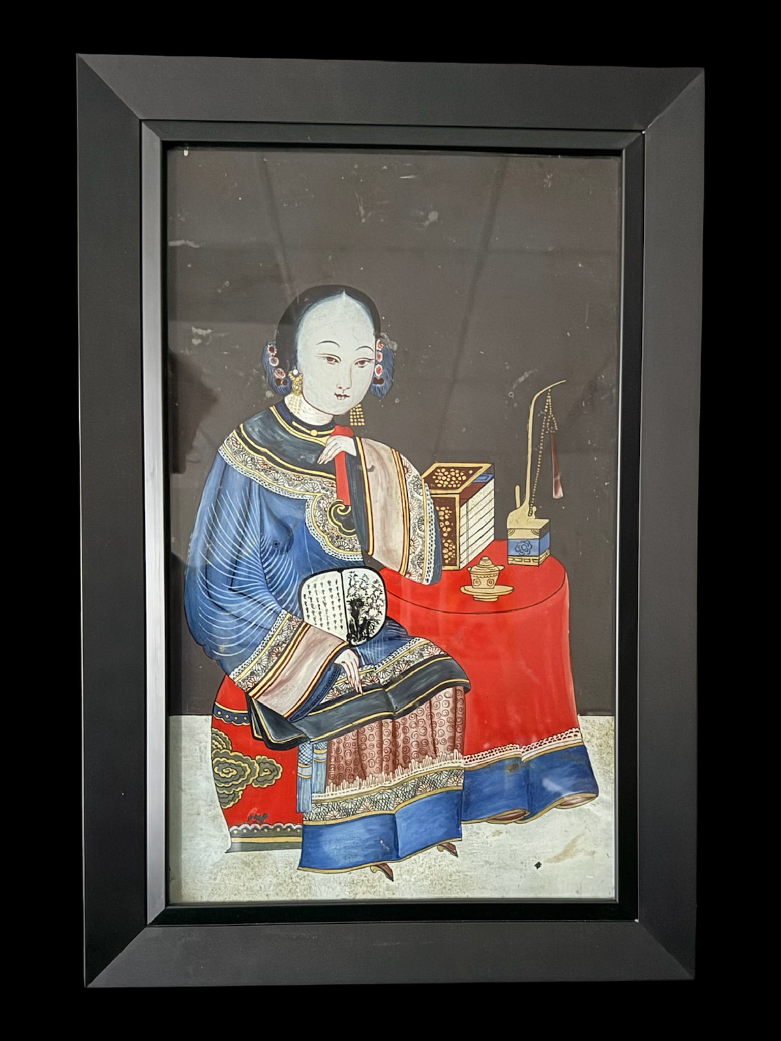 Qing Dynasty Reverse Painting on Glass: This is a Qing Dynasty Chinese export reverse painting on glass. It depicts a traditional Chinese “beauty” in an elegant, informal silk robe, seated next to a table displaying typical scholarl
